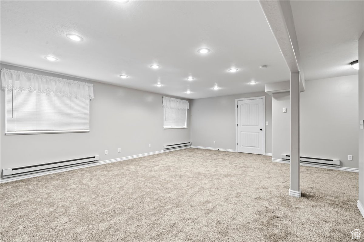 Basement featuring carpet flooring and a baseboard heating unit