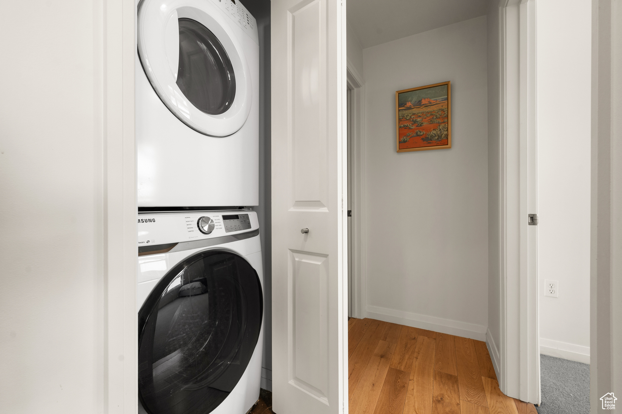 Clothes washing area featuring light hardwood / wood-style floors and stacked washer and dryer