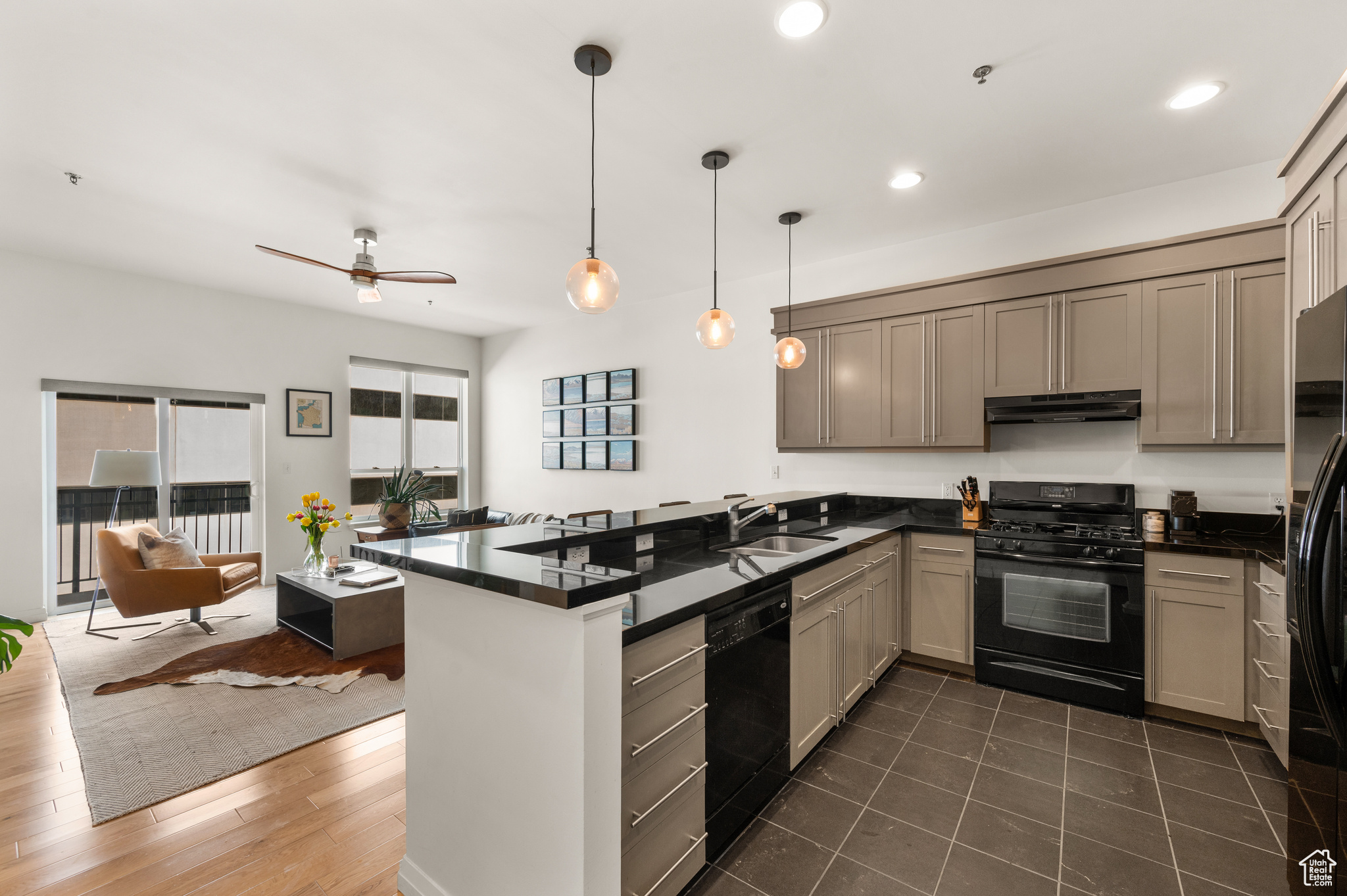 Kitchen featuring dark tile floors, black appliances, kitchen peninsula, sink, and ceiling fan