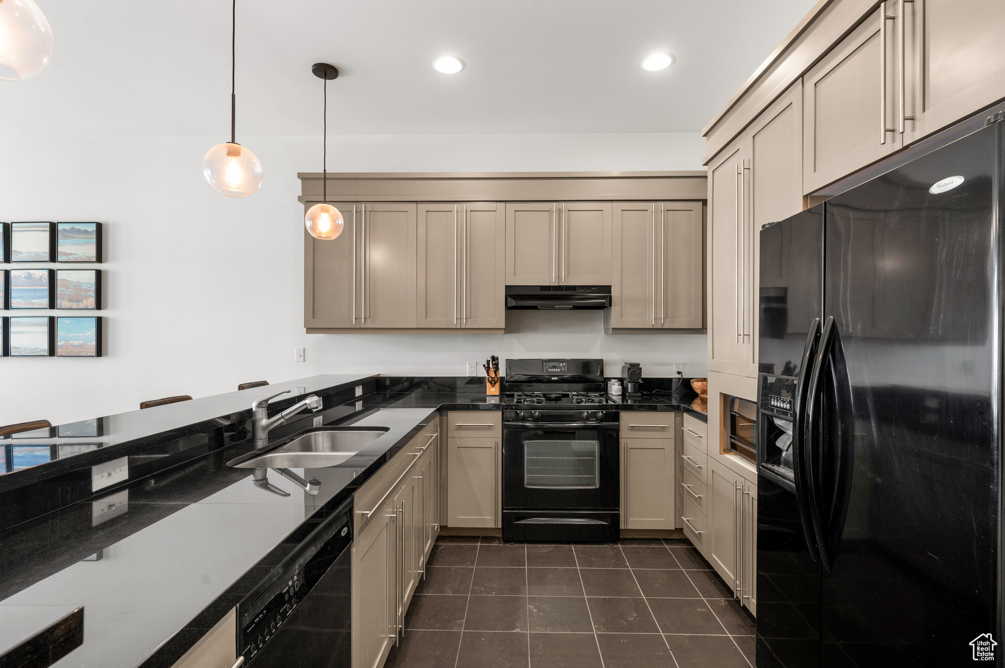 Kitchen featuring sink, pendant lighting, dark tile floors, and black appliances