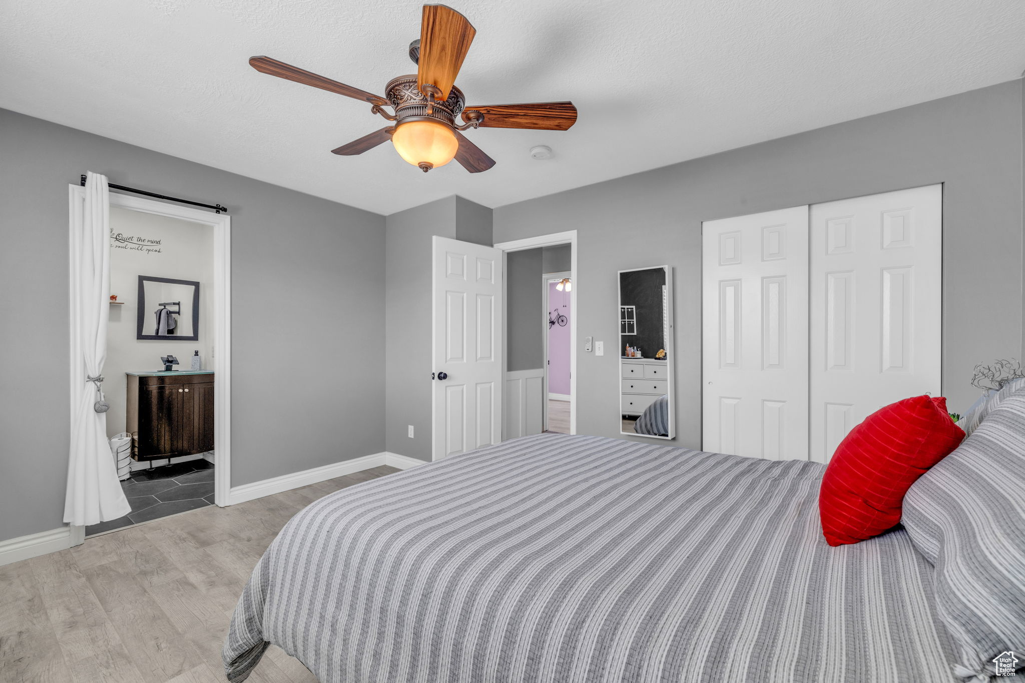 Bedroom with ensuite bath, ceiling fan, hardwood / wood-style flooring, and a closet
