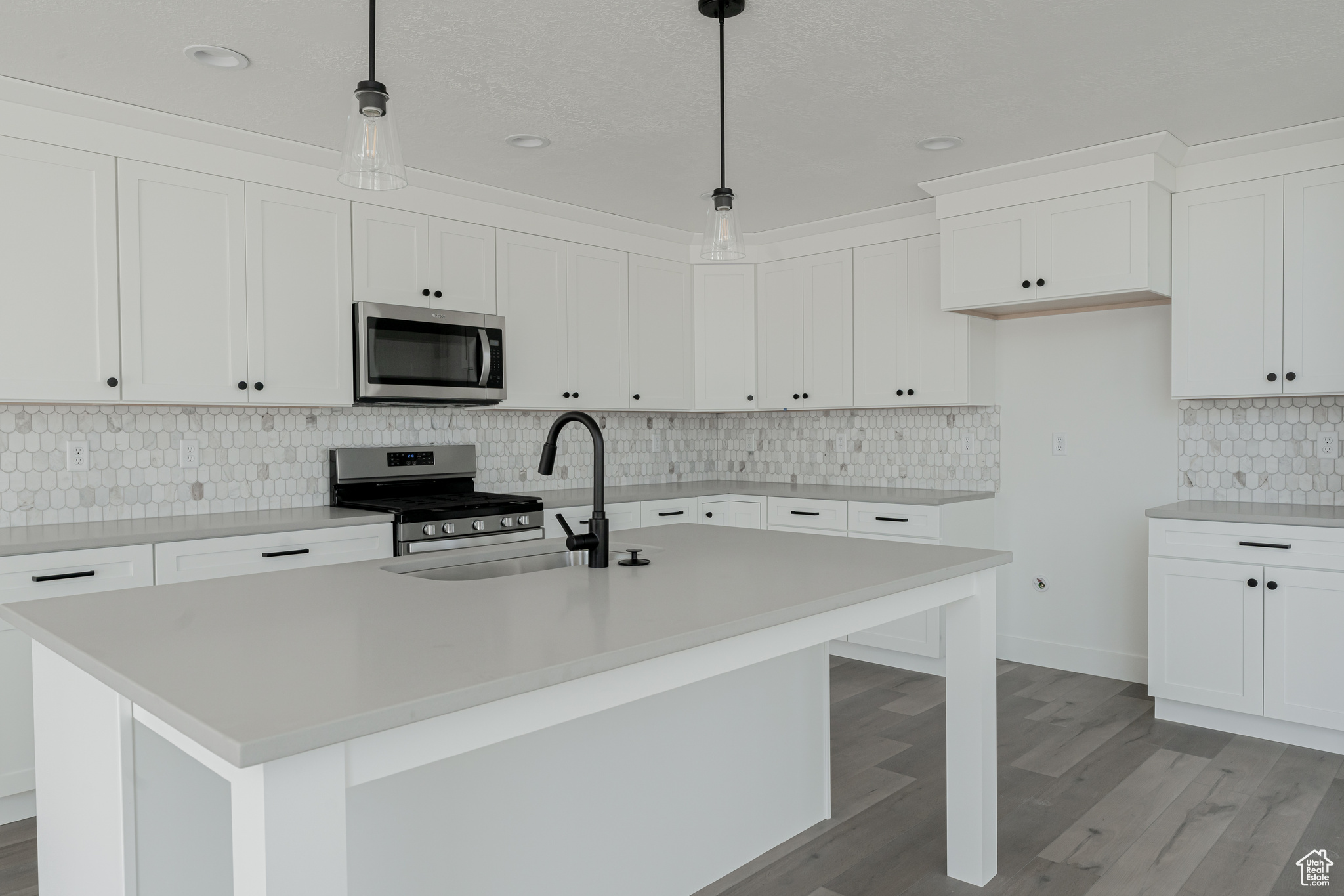 Kitchen with an island with sink, decorative light fixtures, and appliances with stainless steel finishes