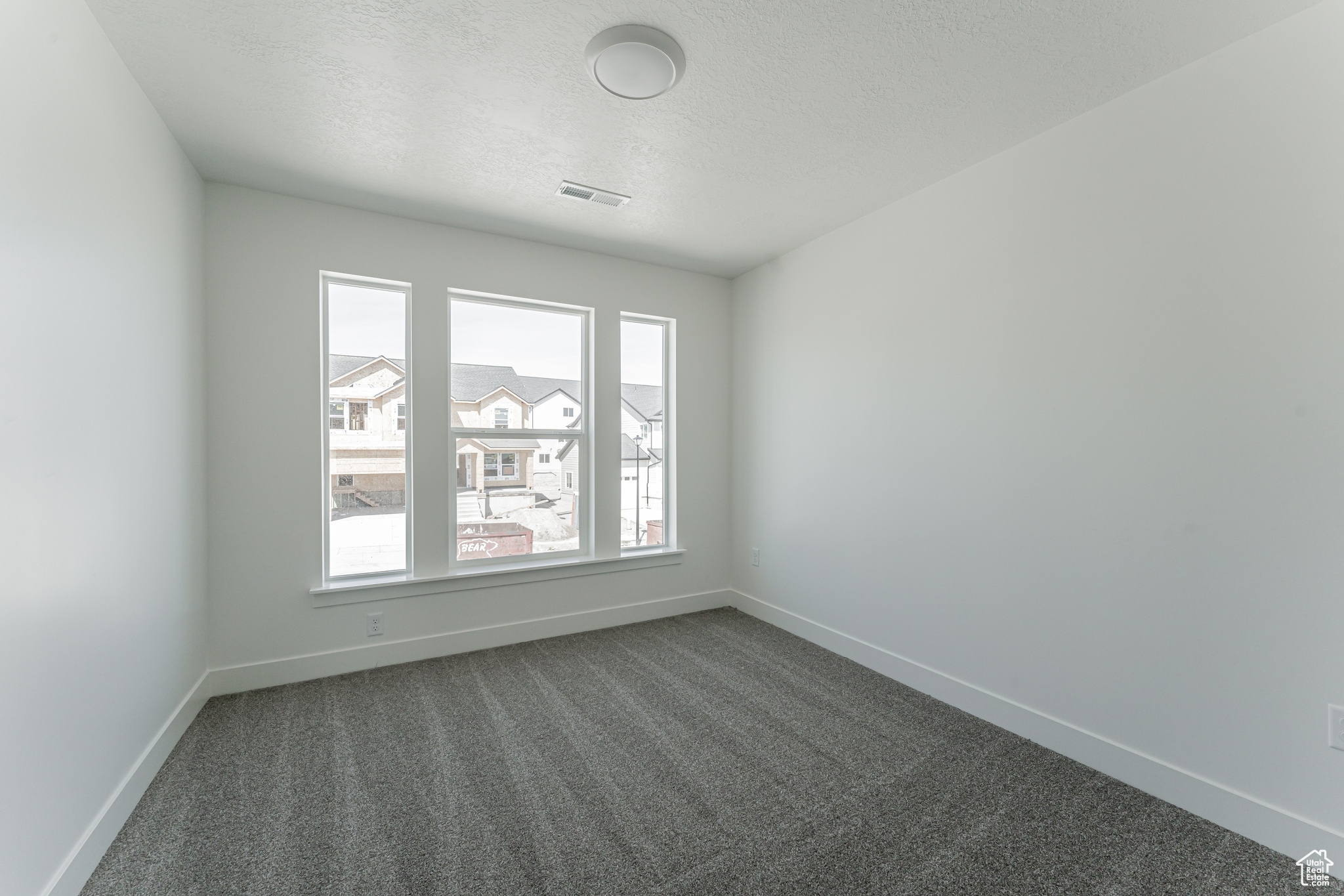 Carpeted spare room featuring a textured ceiling