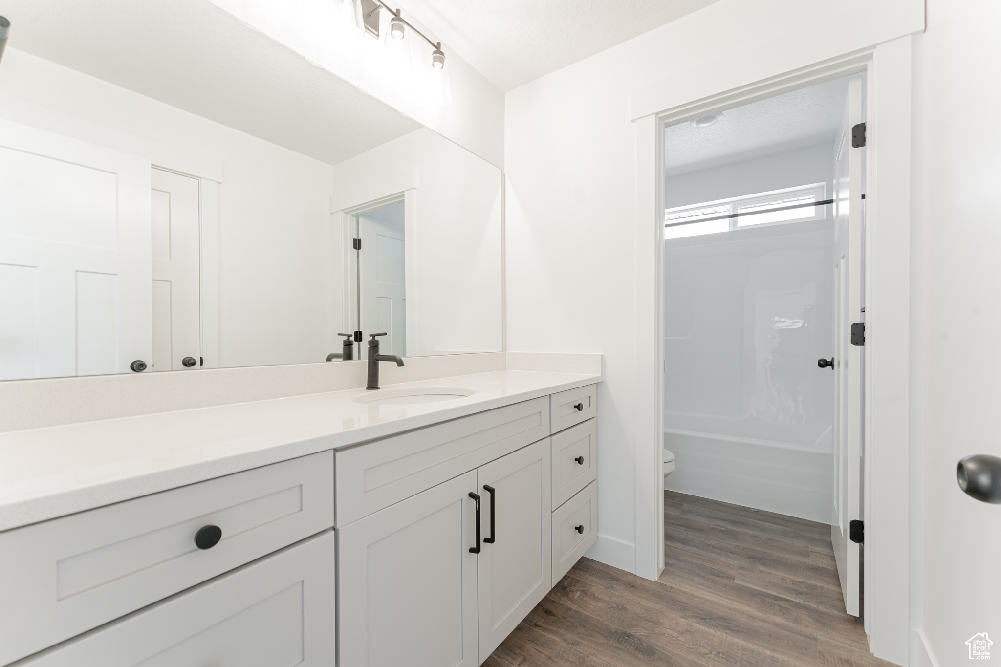 Full bathroom with hardwood / wood-style flooring, bathing tub / shower combination, toilet, and vanity