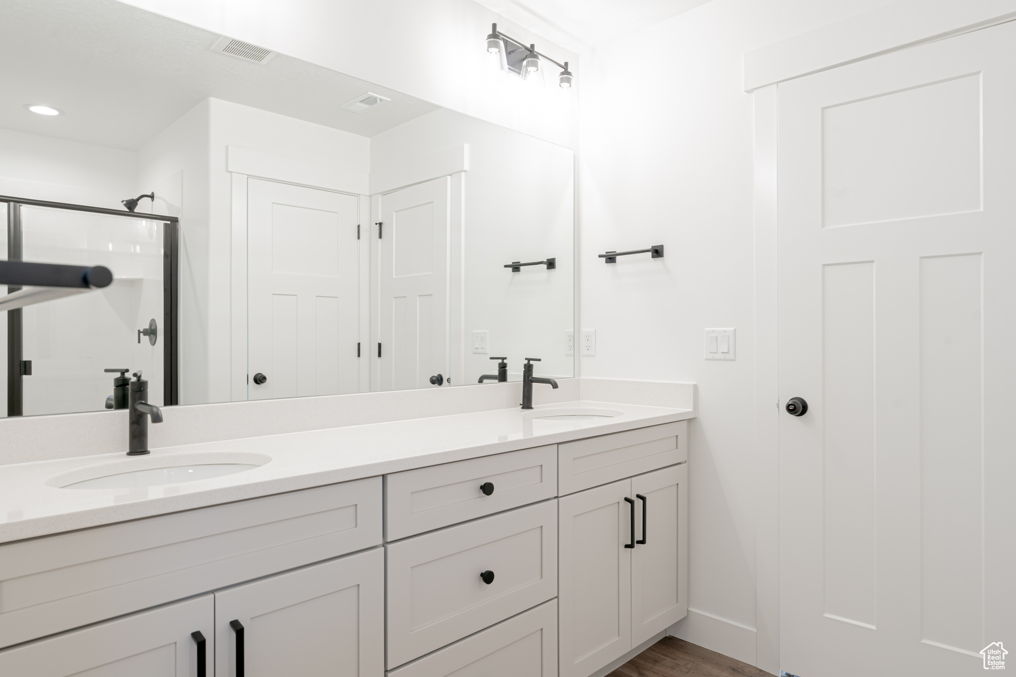 Bathroom with double vanity and hardwood / wood-style flooring