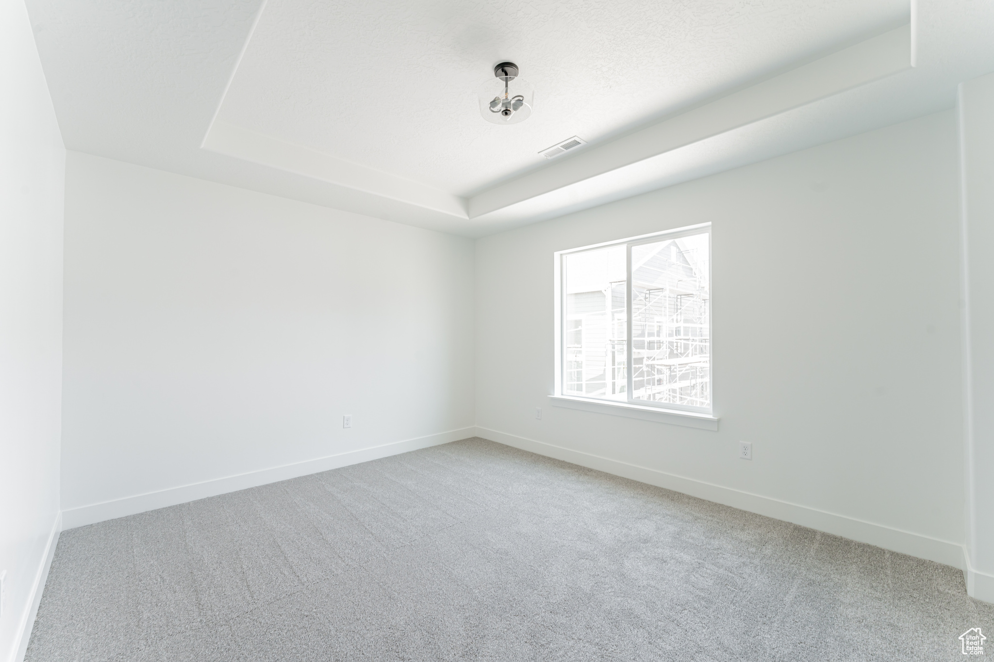 Carpeted empty room with a tray ceiling