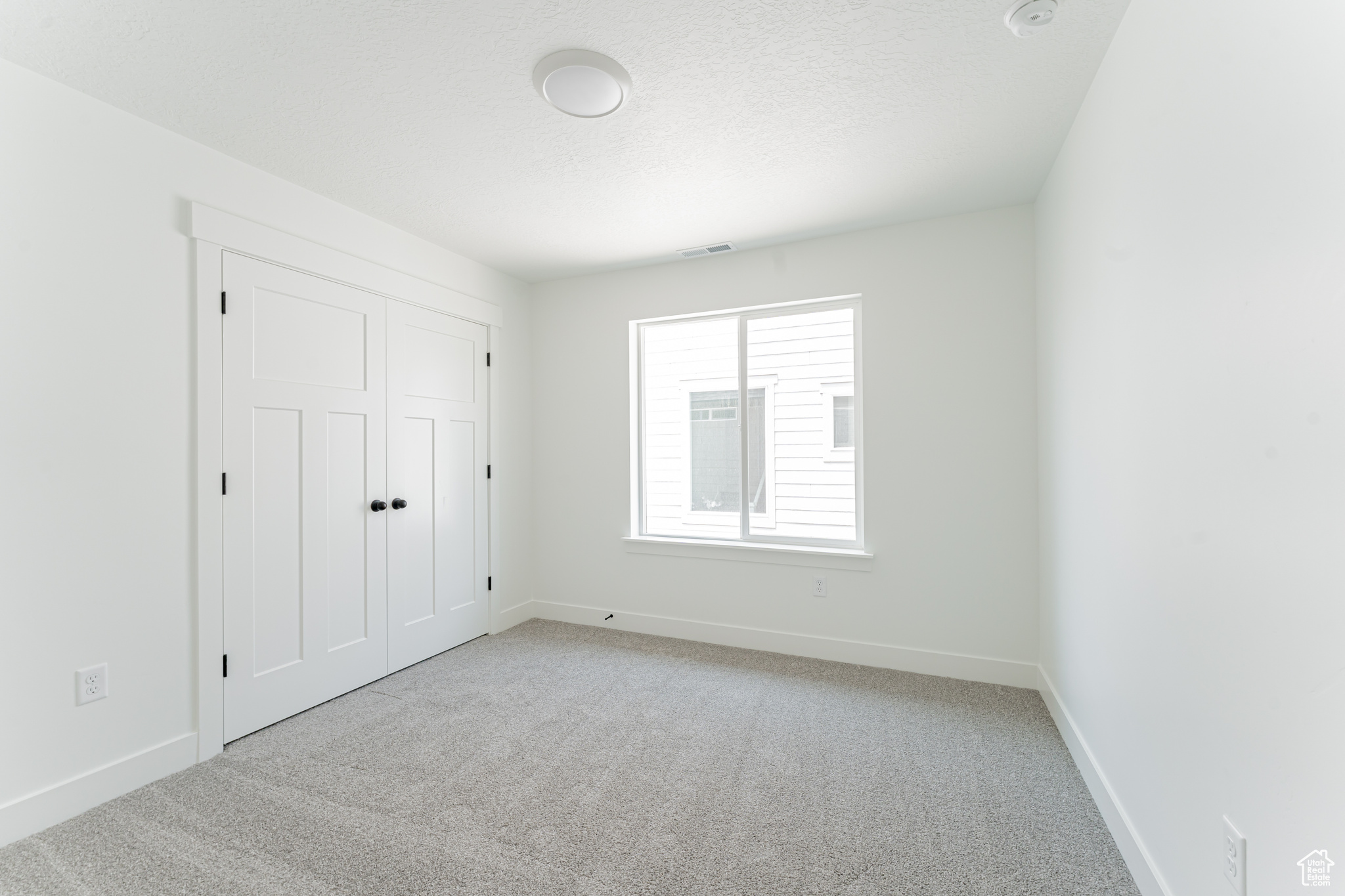 Unfurnished bedroom with light carpet and a closet