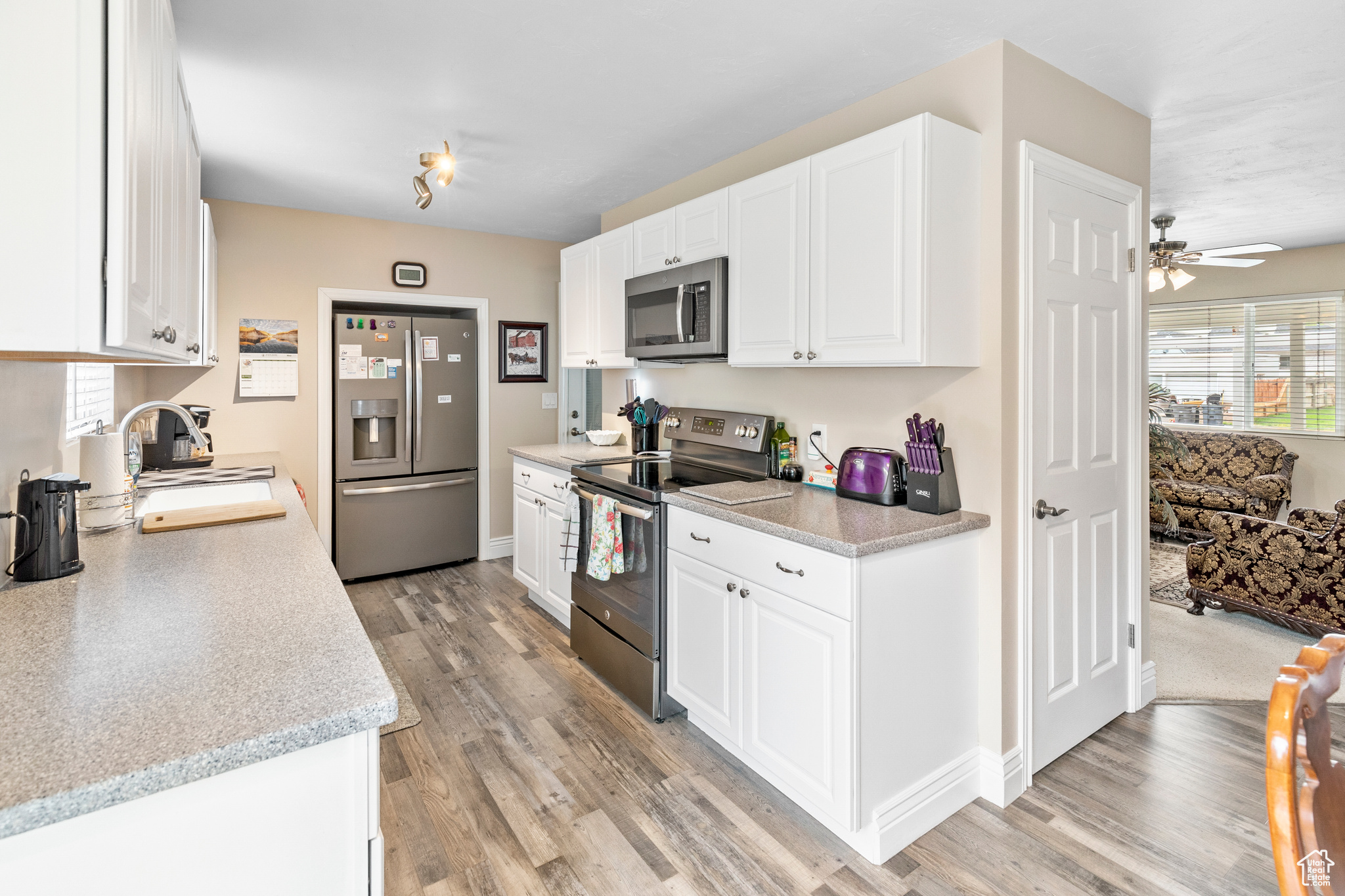 Kitchen featuring light hardwood / wood-style floors, appliances with stainless steel finishes, white cabinetry, and sink