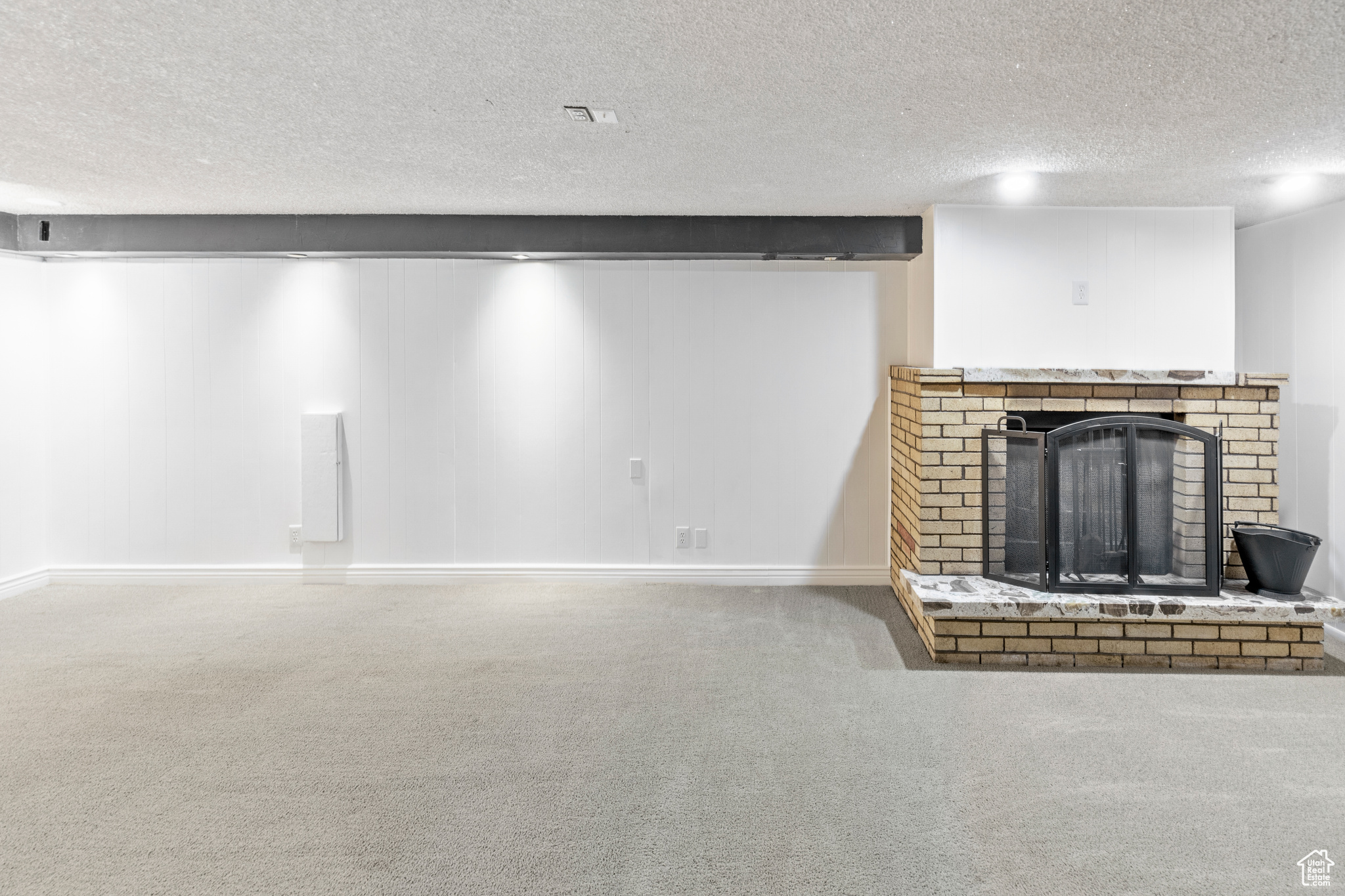 Unfurnished living room with a brick fireplace, carpet floors, and a textured ceiling