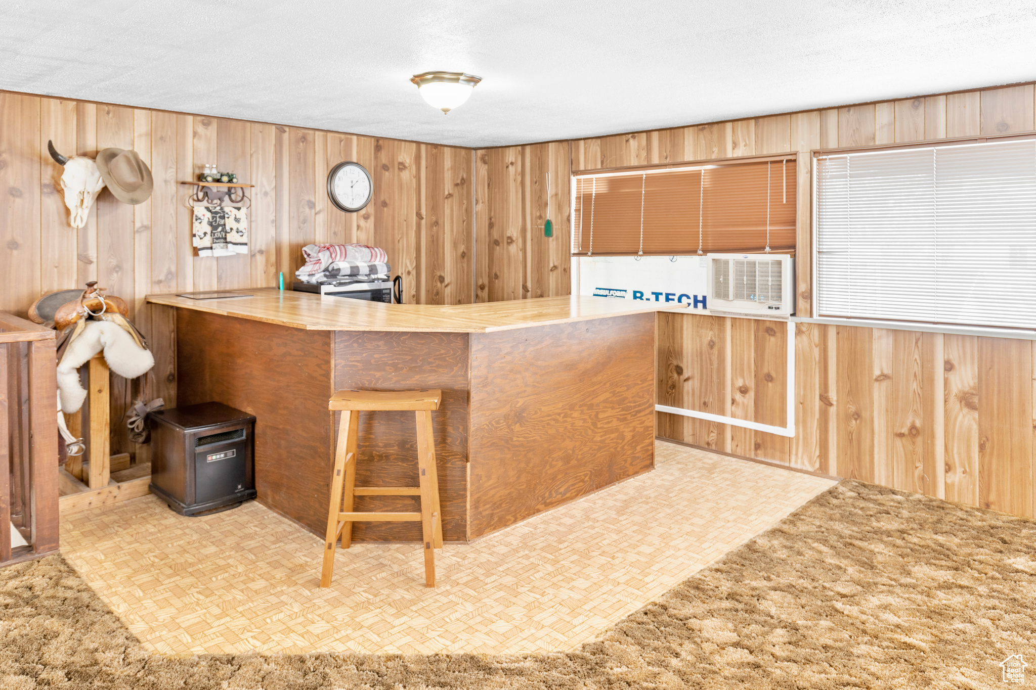 Kitchen with light colored carpet, a kitchen bar, kitchen peninsula, and wooden walls