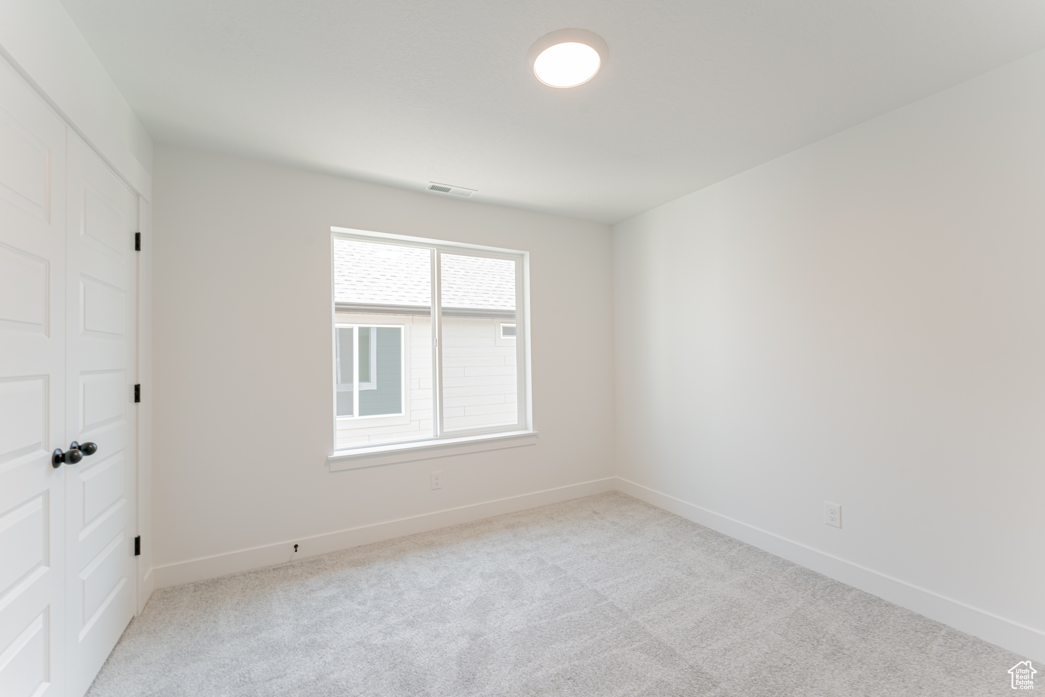 Empty room featuring light colored carpet