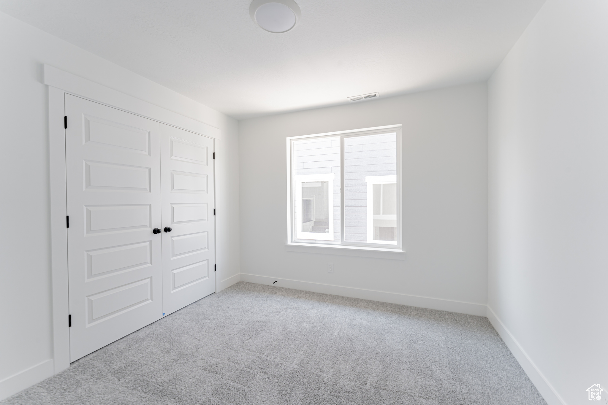 Unfurnished bedroom with light colored carpet and a closet