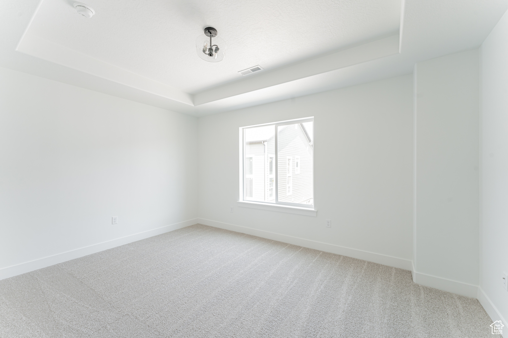 Carpeted empty room with a raised ceiling