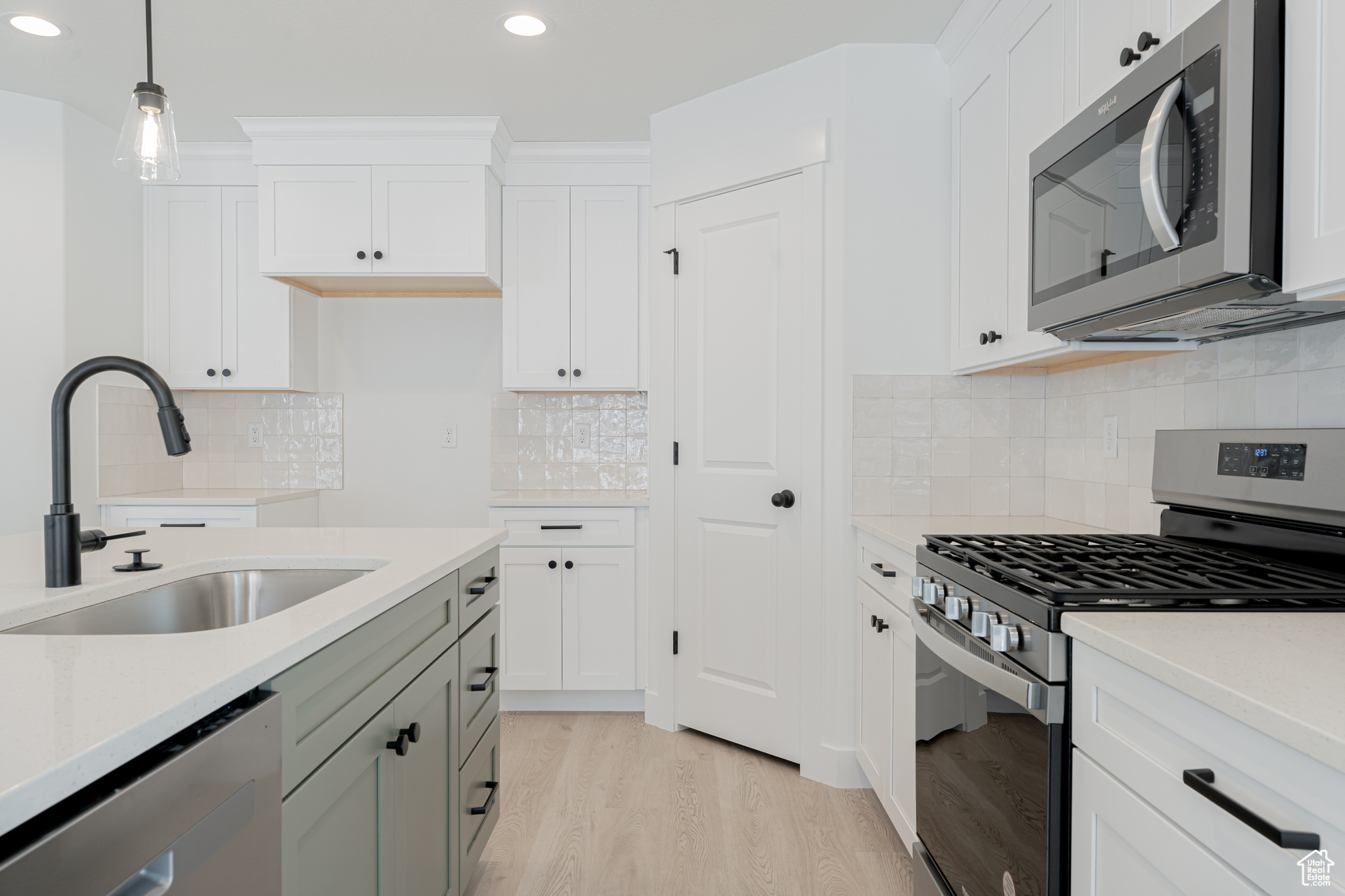 Kitchen featuring decorative light fixtures, stainless steel appliances, decorative backsplash, sink, and light hardwood / wood-style flooring