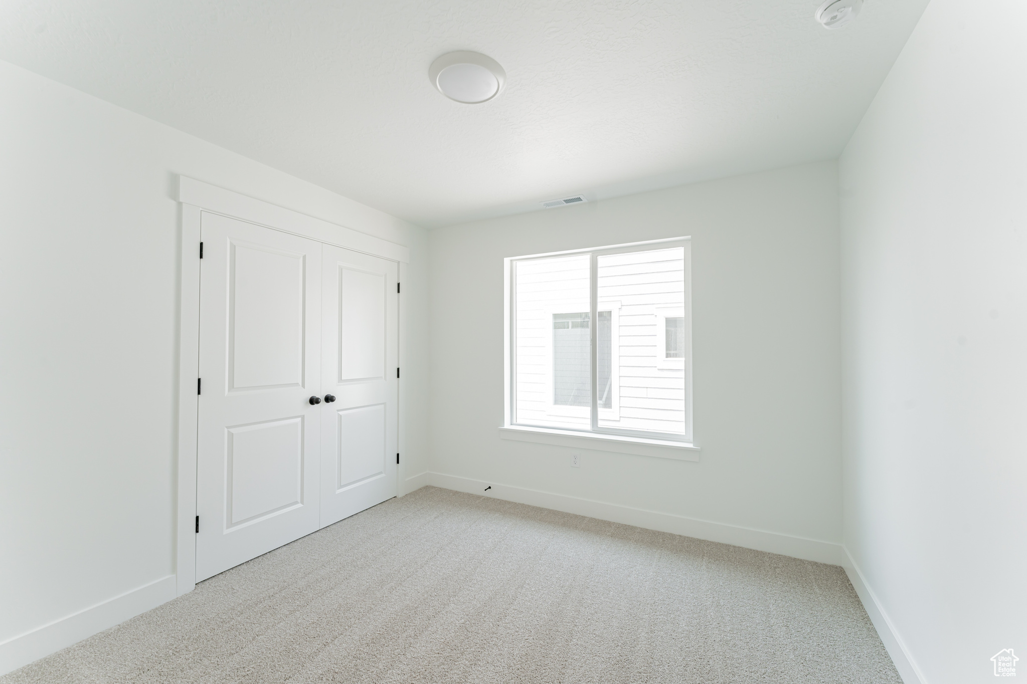 Unfurnished bedroom with light carpet and a closet