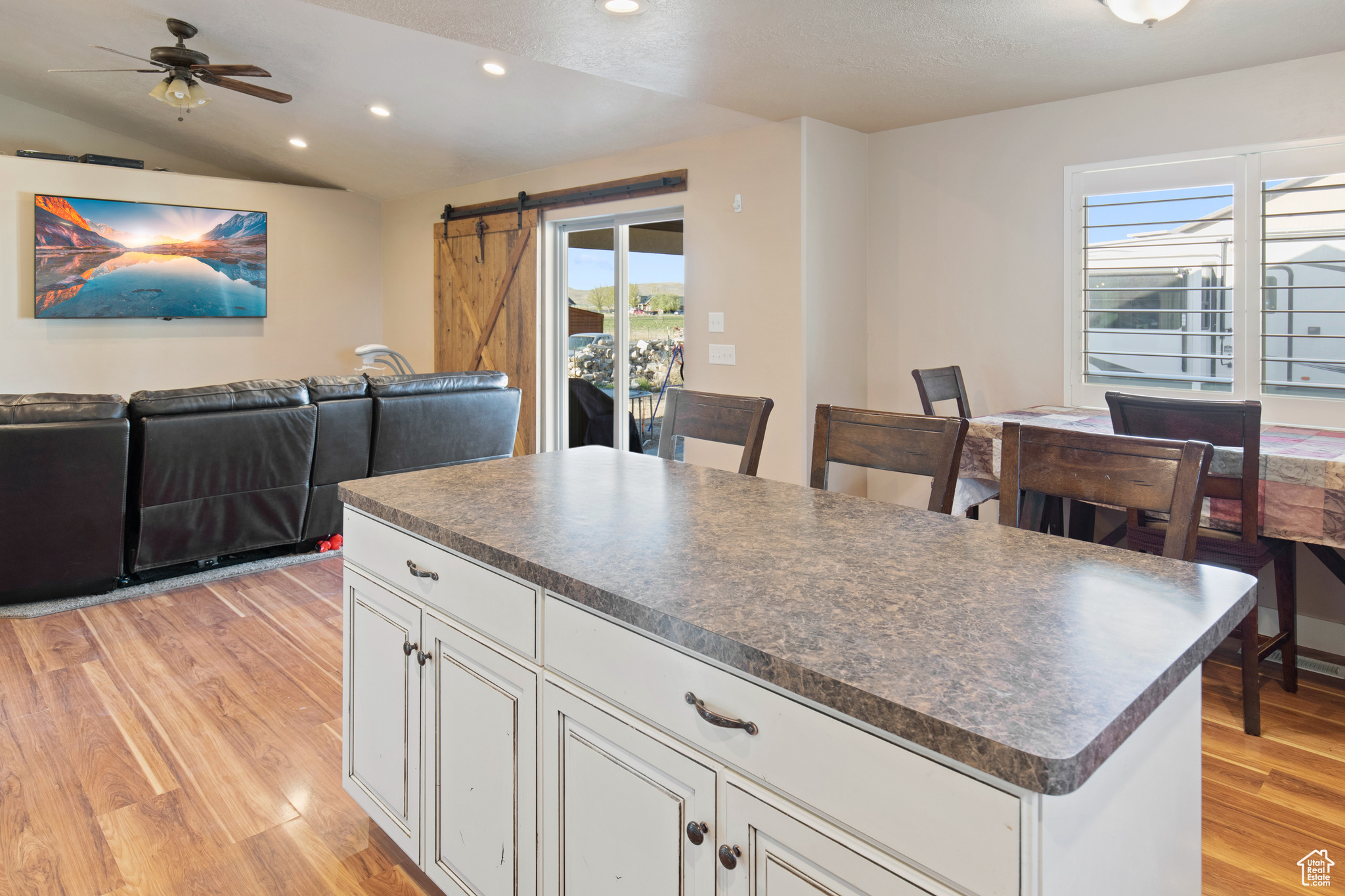 Kitchen featuring a barn door, ceiling fan, vaulted ceiling, light hardwood / wood-style floors, and a center island