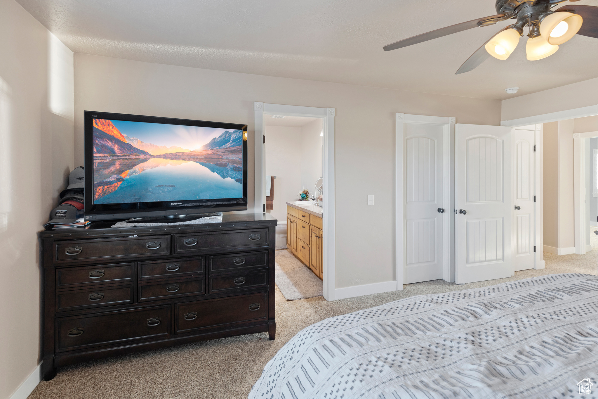 Carpeted bedroom featuring ceiling fan and ensuite bath