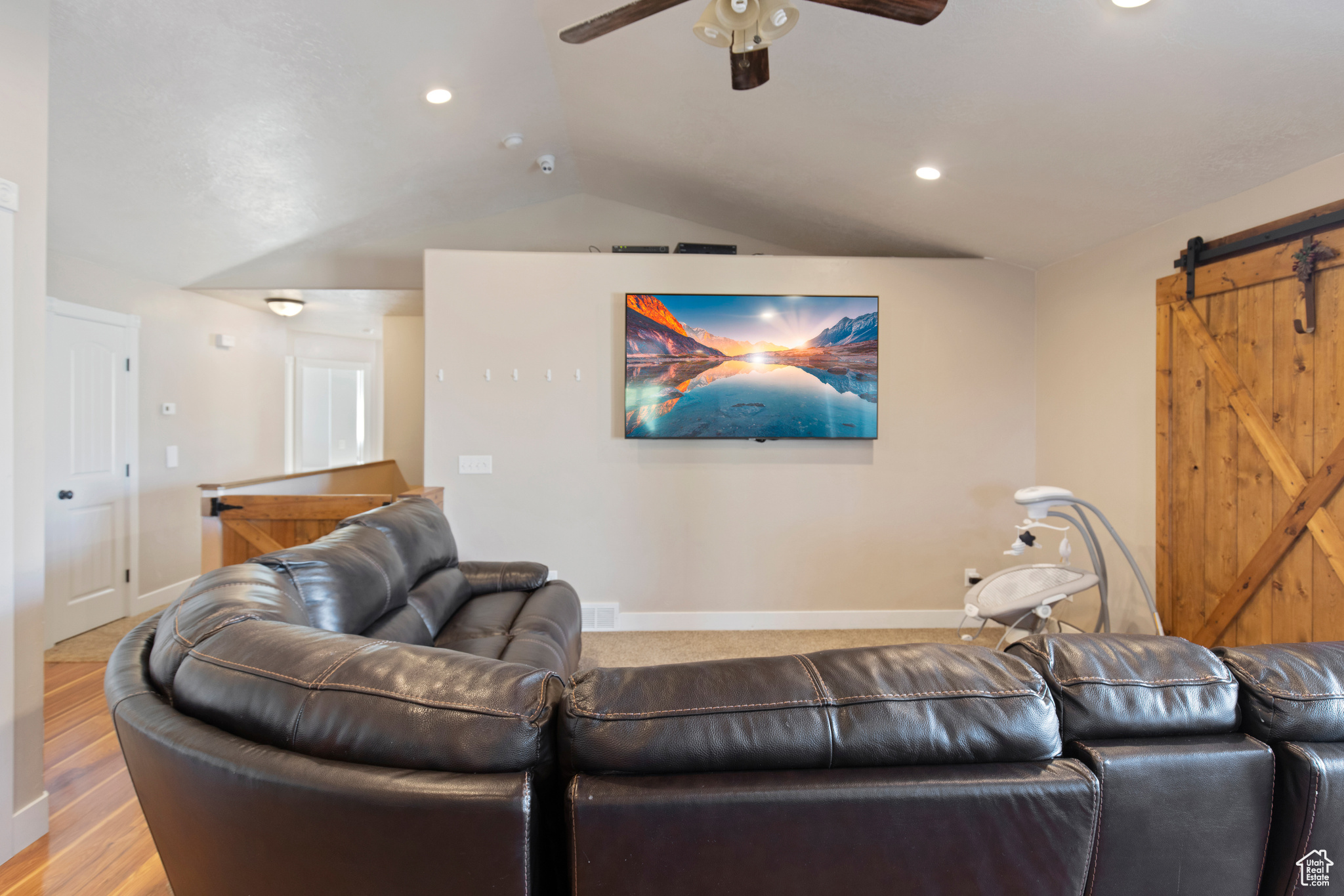 Living room with hardwood / wood-style floors, lofted ceiling, ceiling fan, and a barn door