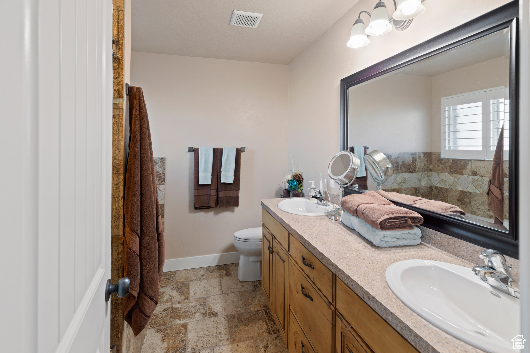 Bathroom featuring toilet, tile flooring, and dual vanity