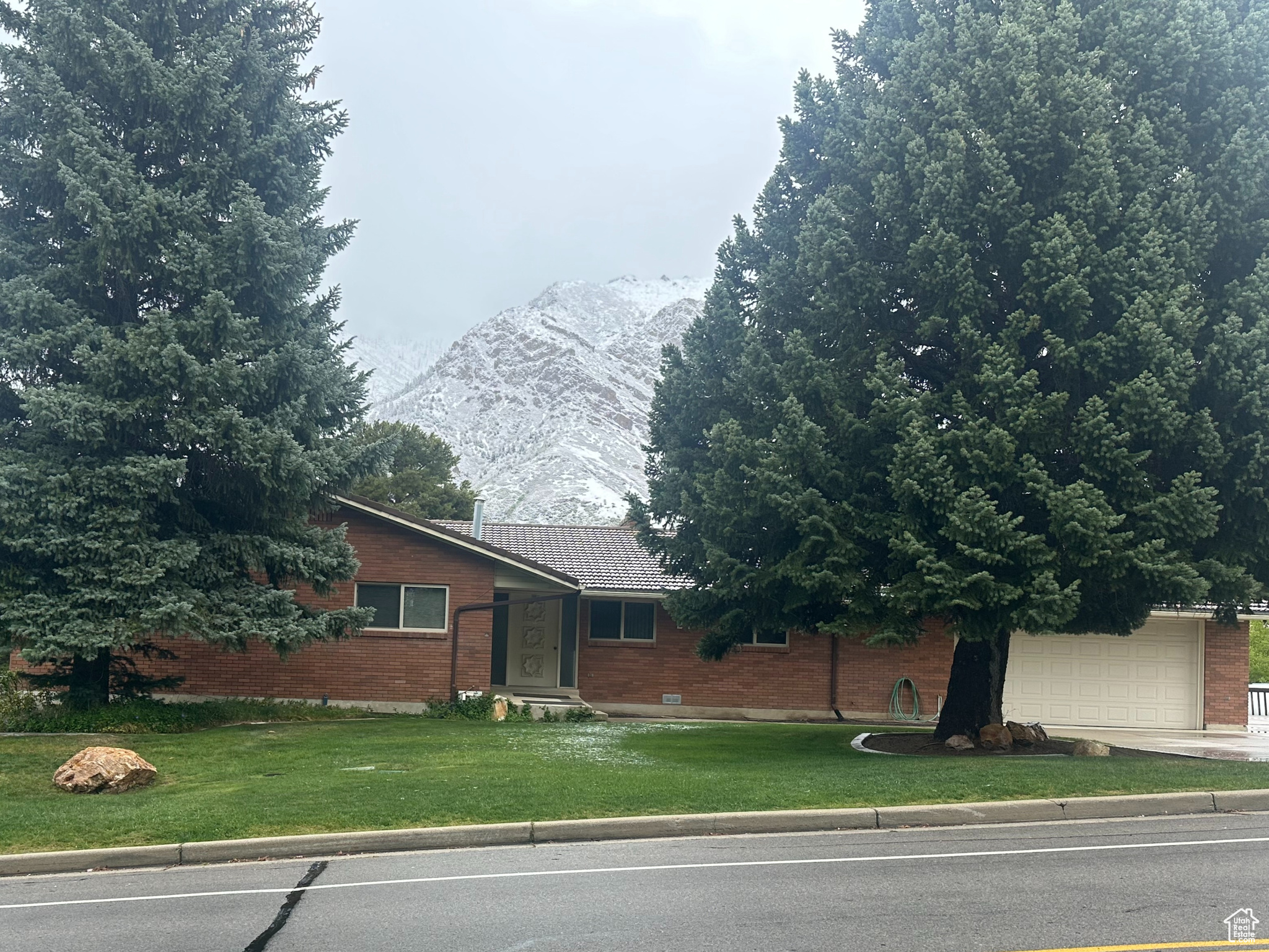 View of front, with fantastic mountain view, large garage, mature landscaping.
