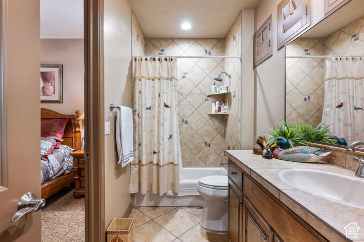 Full bathroom featuring shower / bath combination with curtain, toilet, vanity, and tile flooring