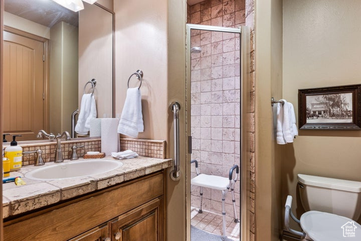 Bathroom featuring a shower with shower door, toilet, and oversized vanity