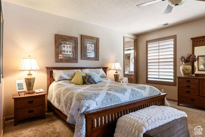 Bedroom featuring a textured ceiling, carpet floors, and ceiling fan