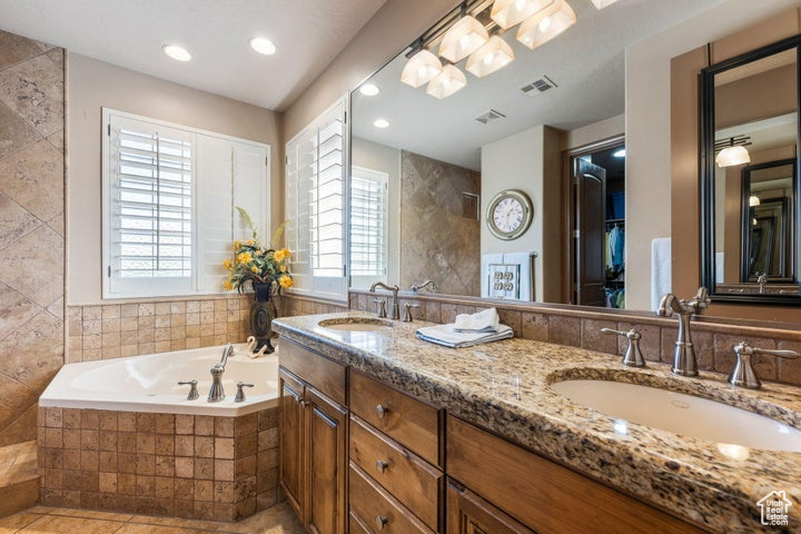 Bathroom with double sink, tiled tub, tile floors, and large vanity