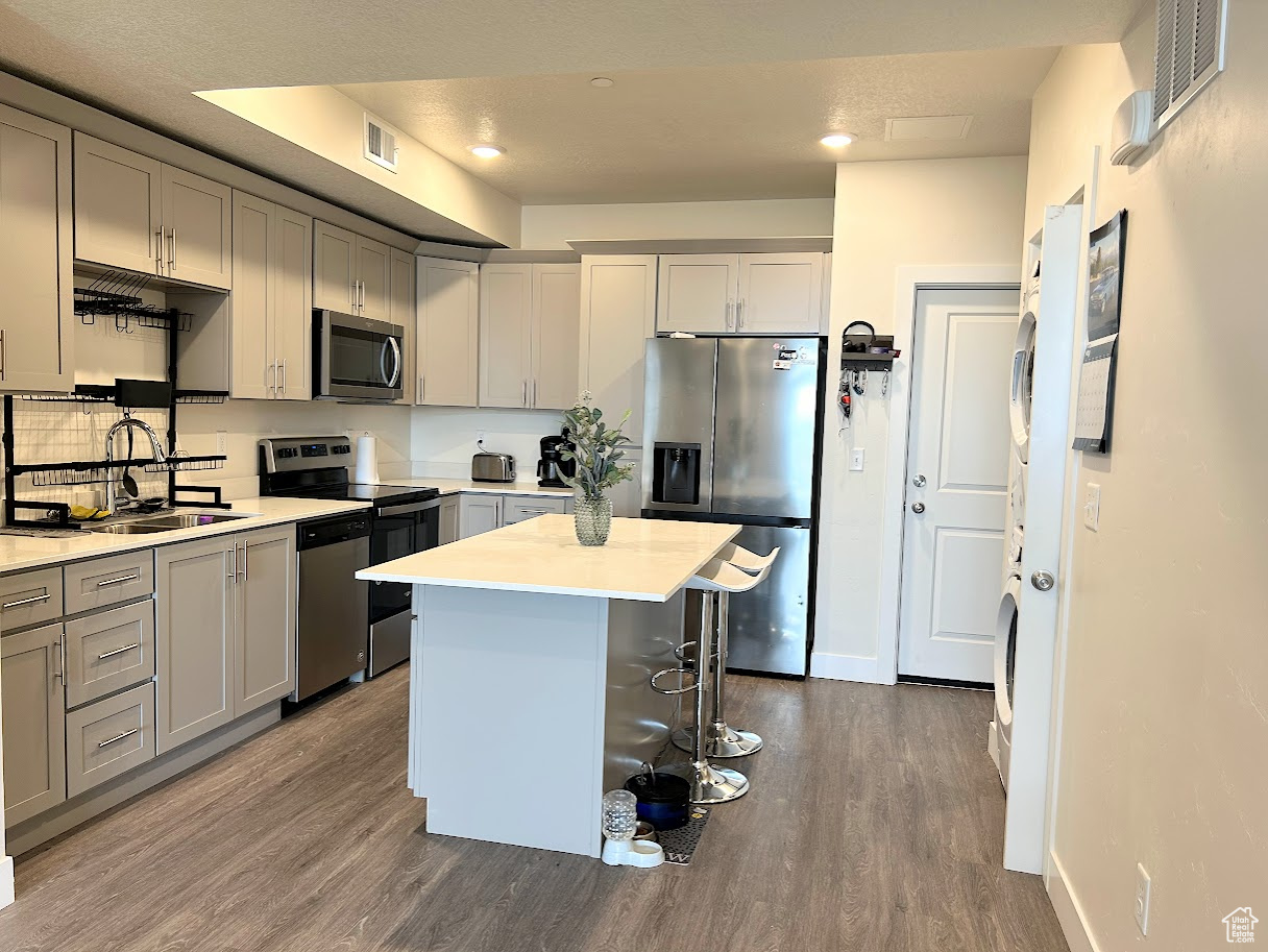 Kitchen featuring a center island, gray cabinetry, hardwood / wood-style floors, appliances with stainless steel finishes, and sink