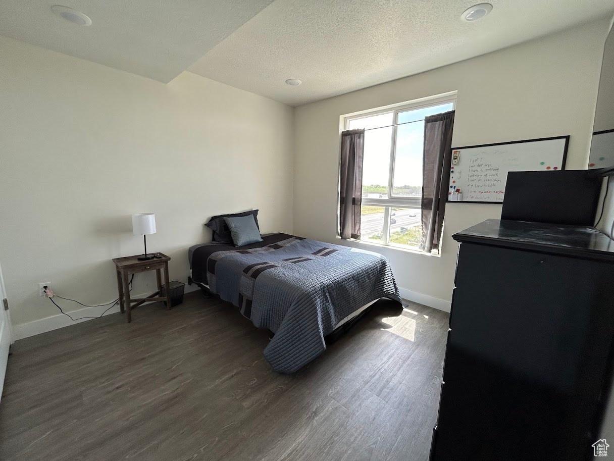 Bedroom with dark hardwood / wood-style flooring and a textured ceiling