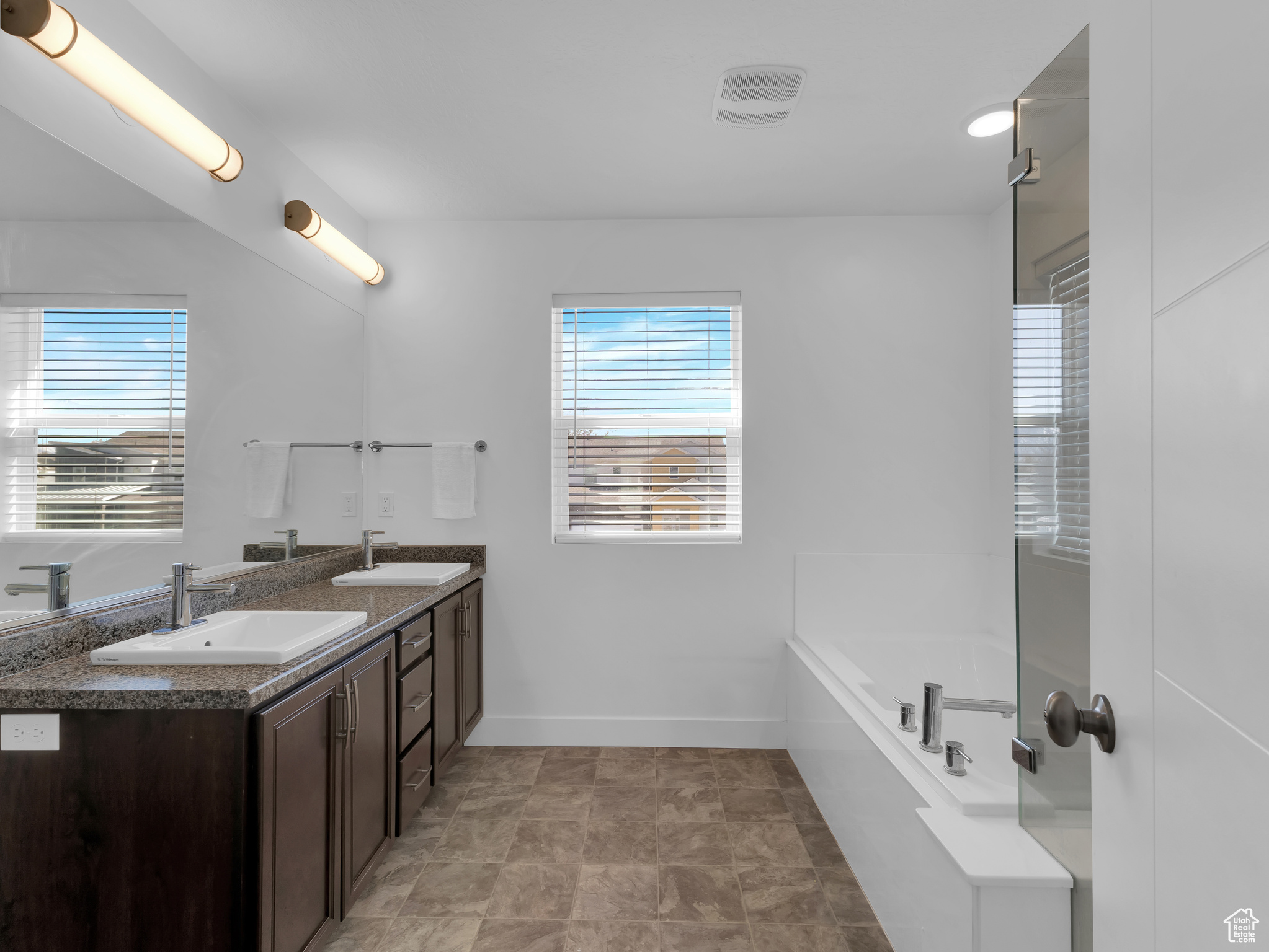 Bathroom featuring a bathing tub, tile floors, and dual vanity