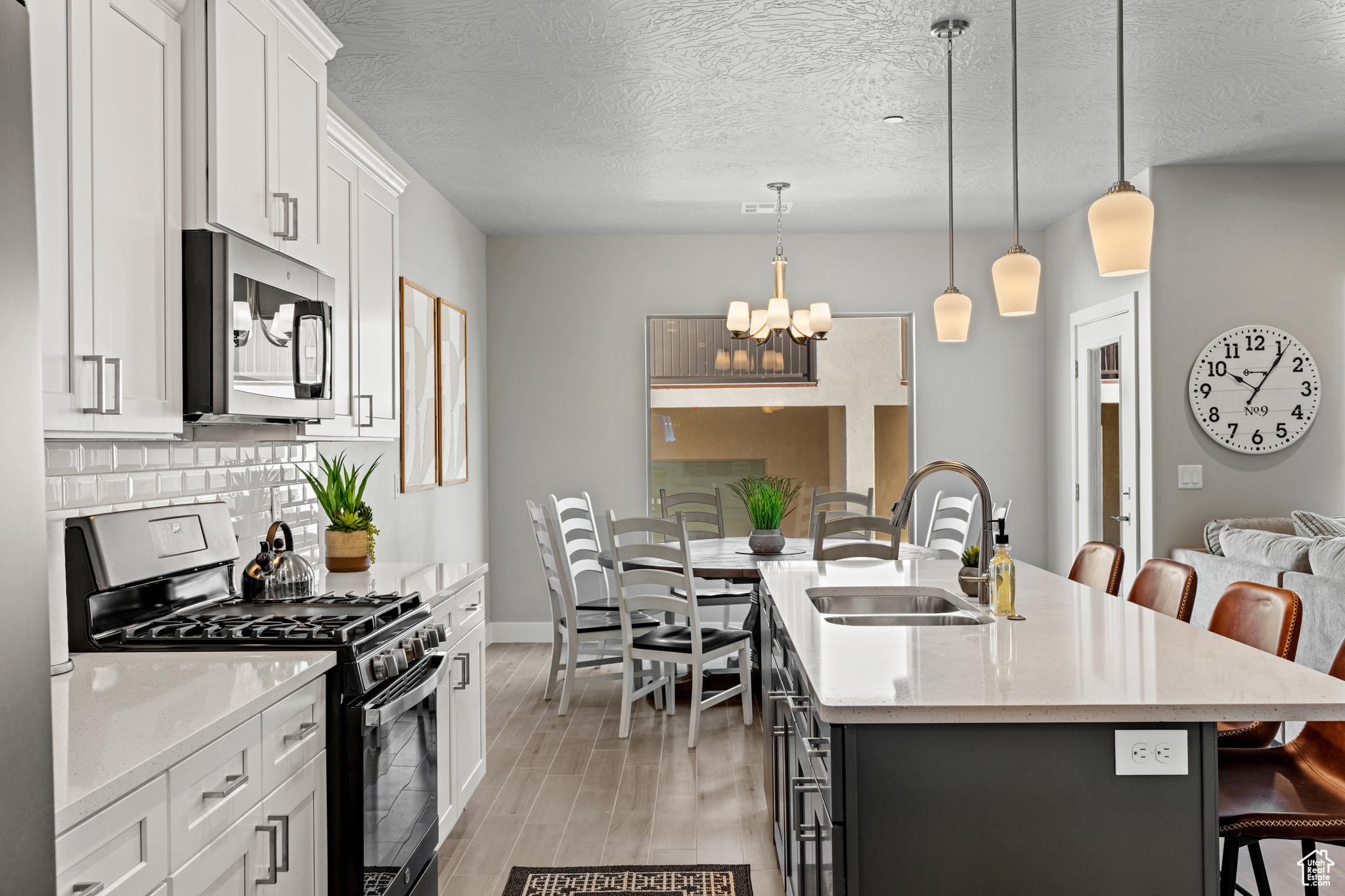 Kitchen featuring a kitchen bar, stainless steel appliances, a kitchen island with sink, sink, and pendant lighting