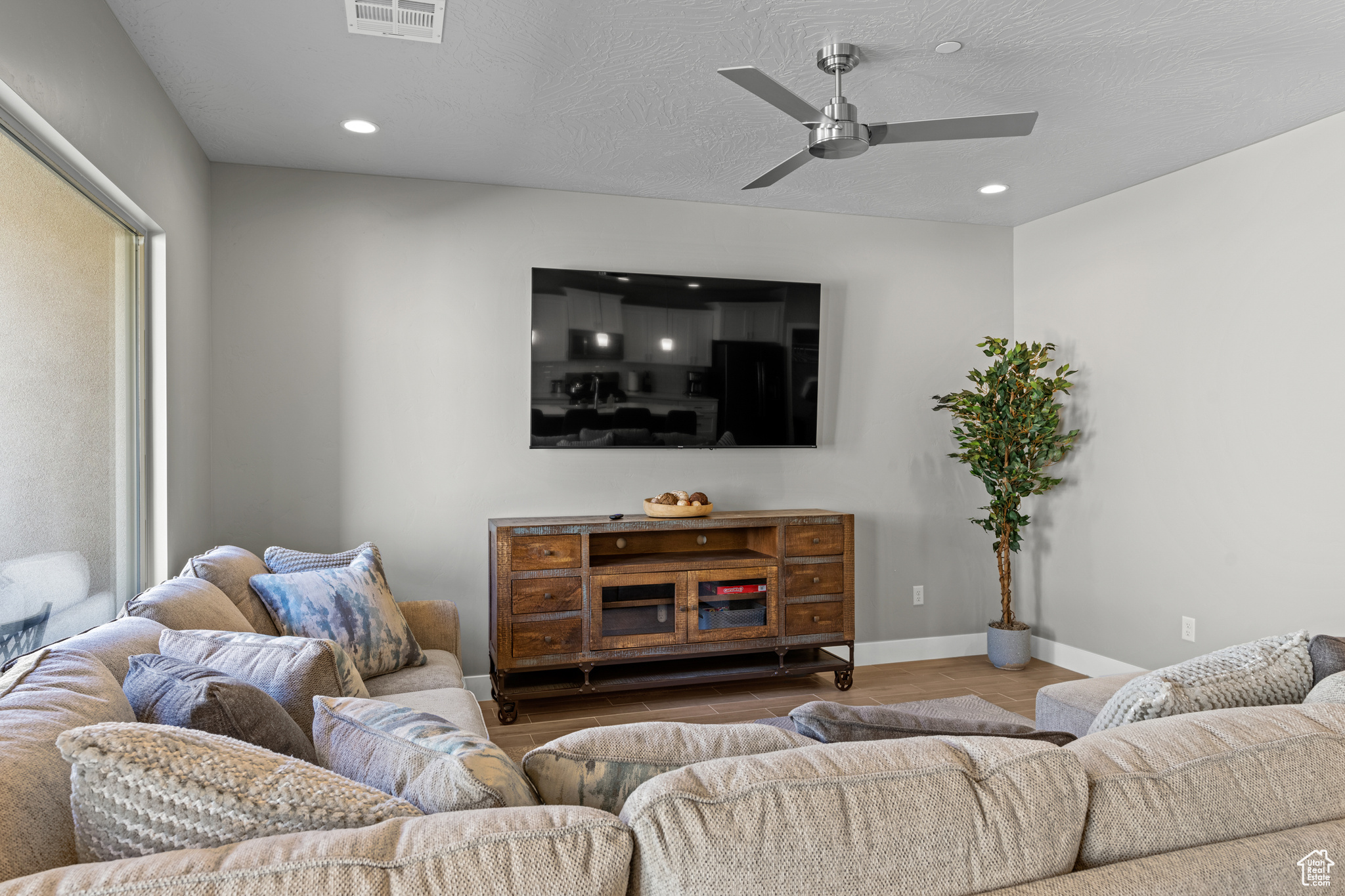Living room with hardwood / wood-style floors, ceiling fan, and a textured ceiling