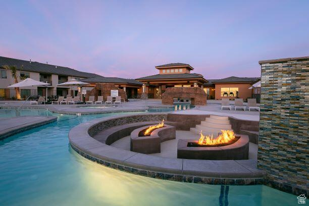 Pool at dusk featuring an outdoor fire pit and a patio area