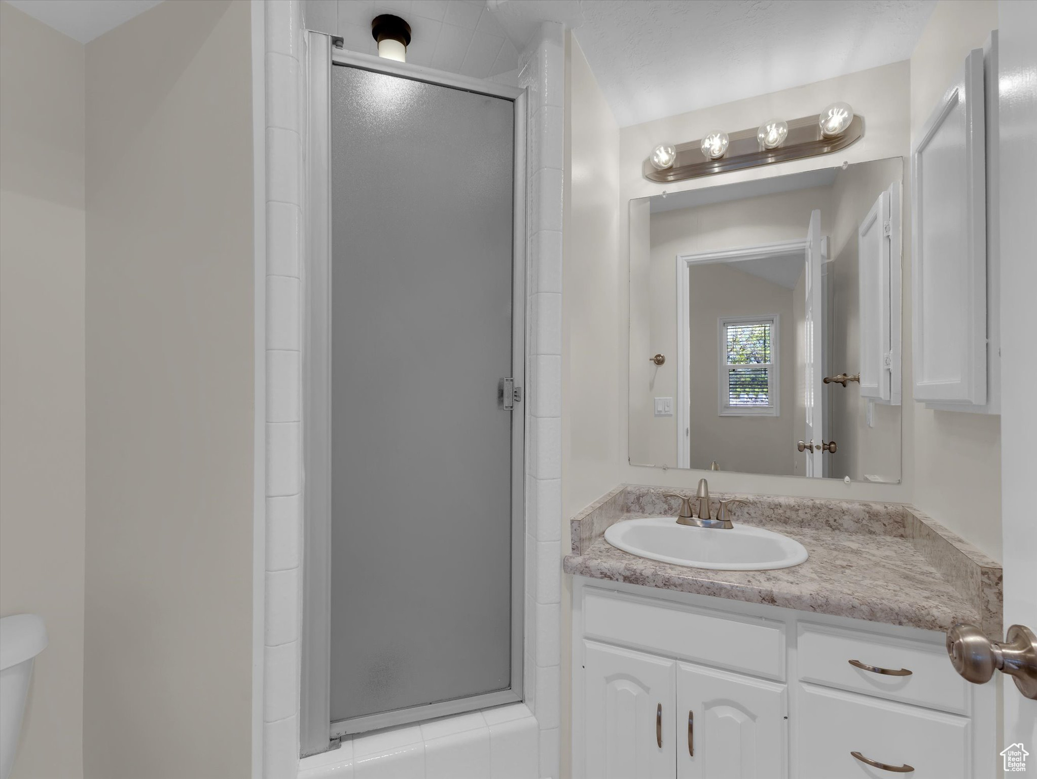 Bathroom with an enclosed shower, toilet, and vanity