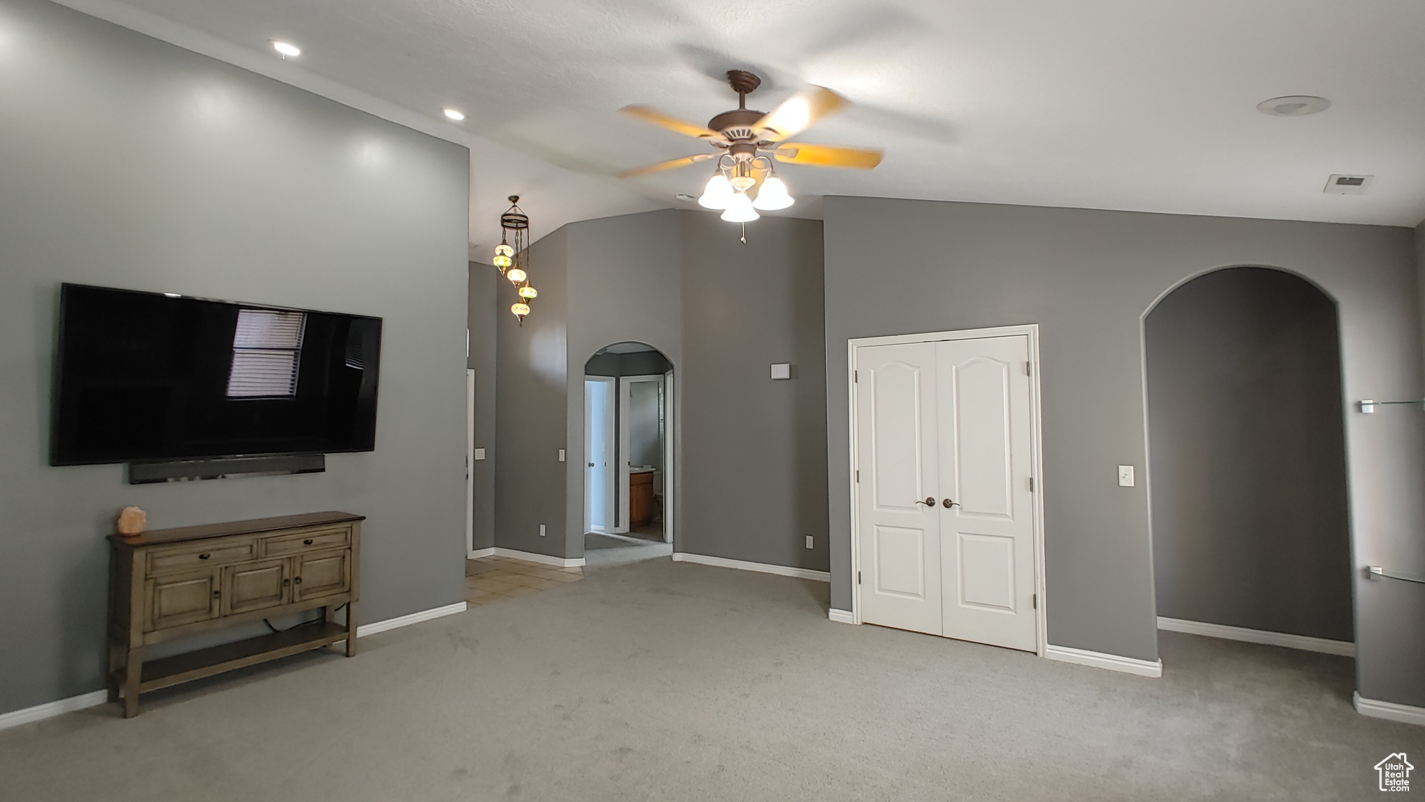 Unfurnished living room with high vaulted ceiling, ceiling fan, and carpet