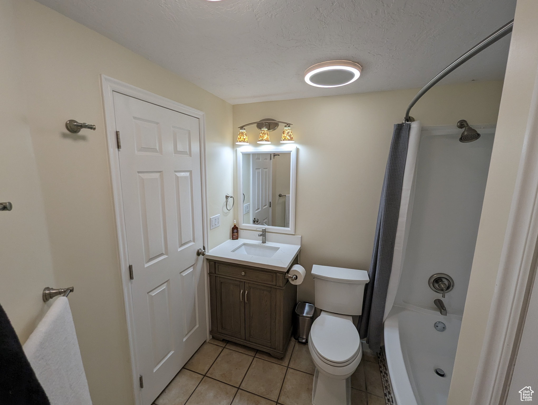 Full bathroom featuring vanity, shower / tub combo, tile floors, and toilet