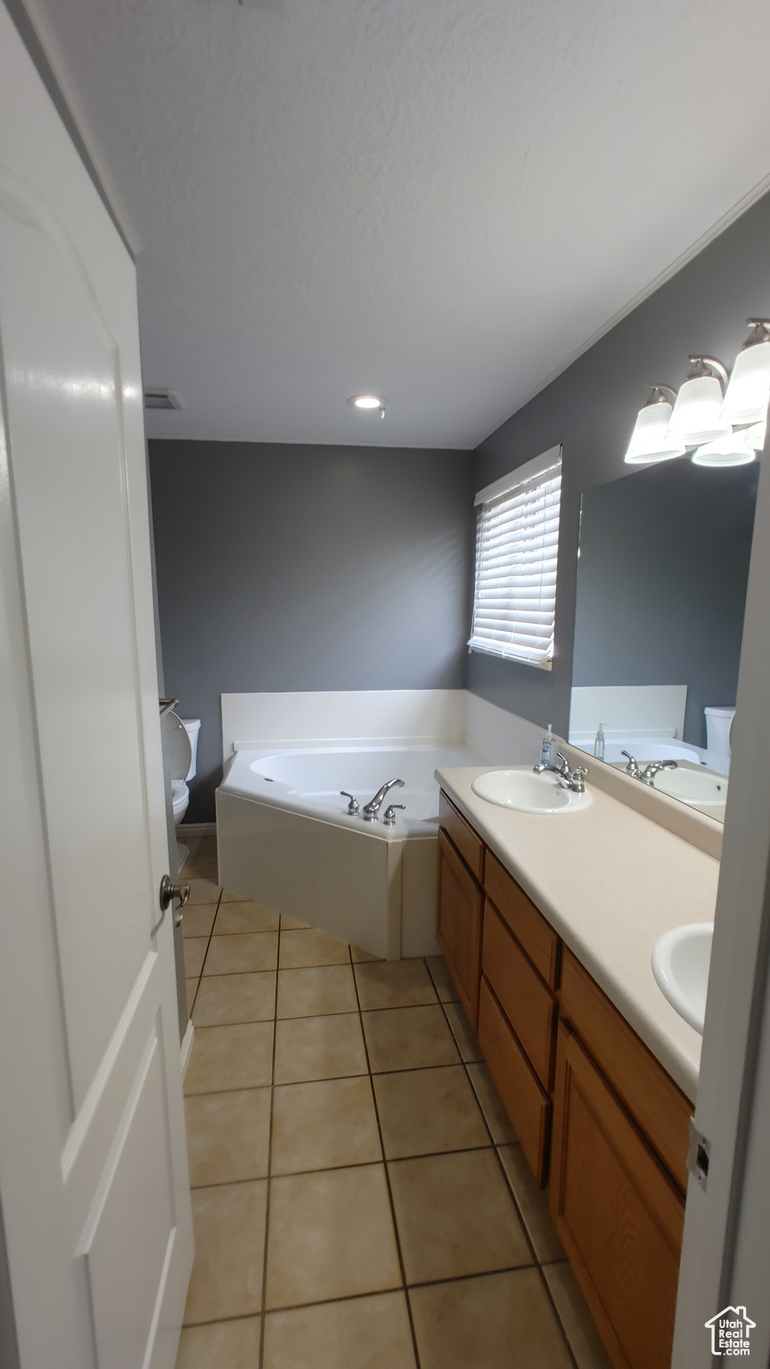 Bathroom featuring tile floors, vanity with extensive cabinet space, and a tub