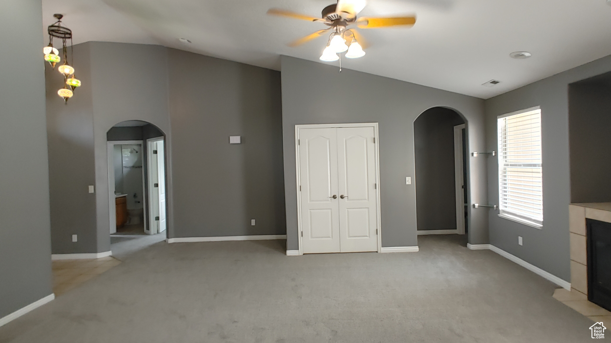 Unfurnished living room with ceiling fan, vaulted ceiling, and carpet flooring
