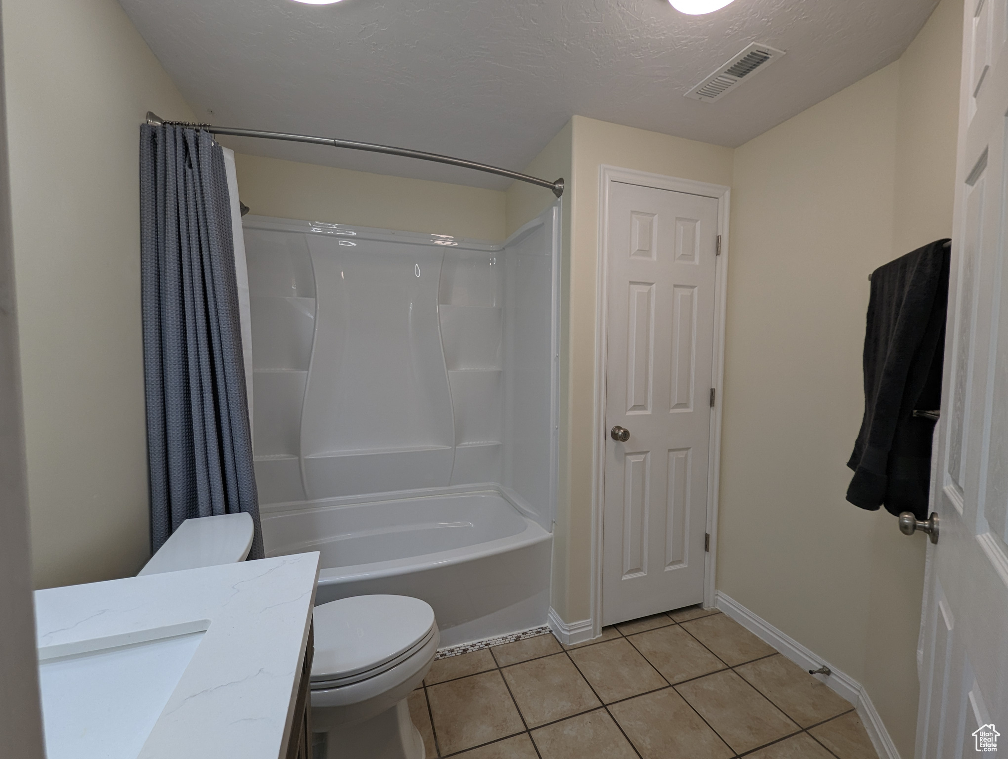 Full bathroom featuring vanity, shower / bath combo, tile floors, and toilet