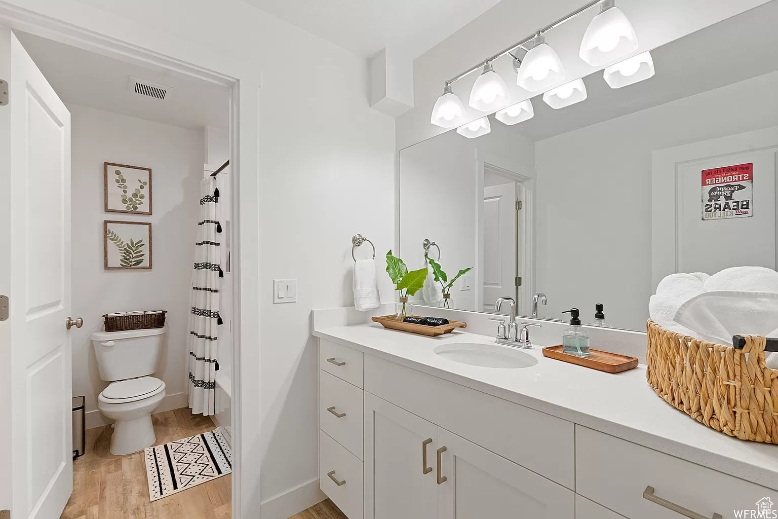 Full bathroom with hardwood / wood-style floors, vanity, toilet, and shower / bath combo with shower curtain