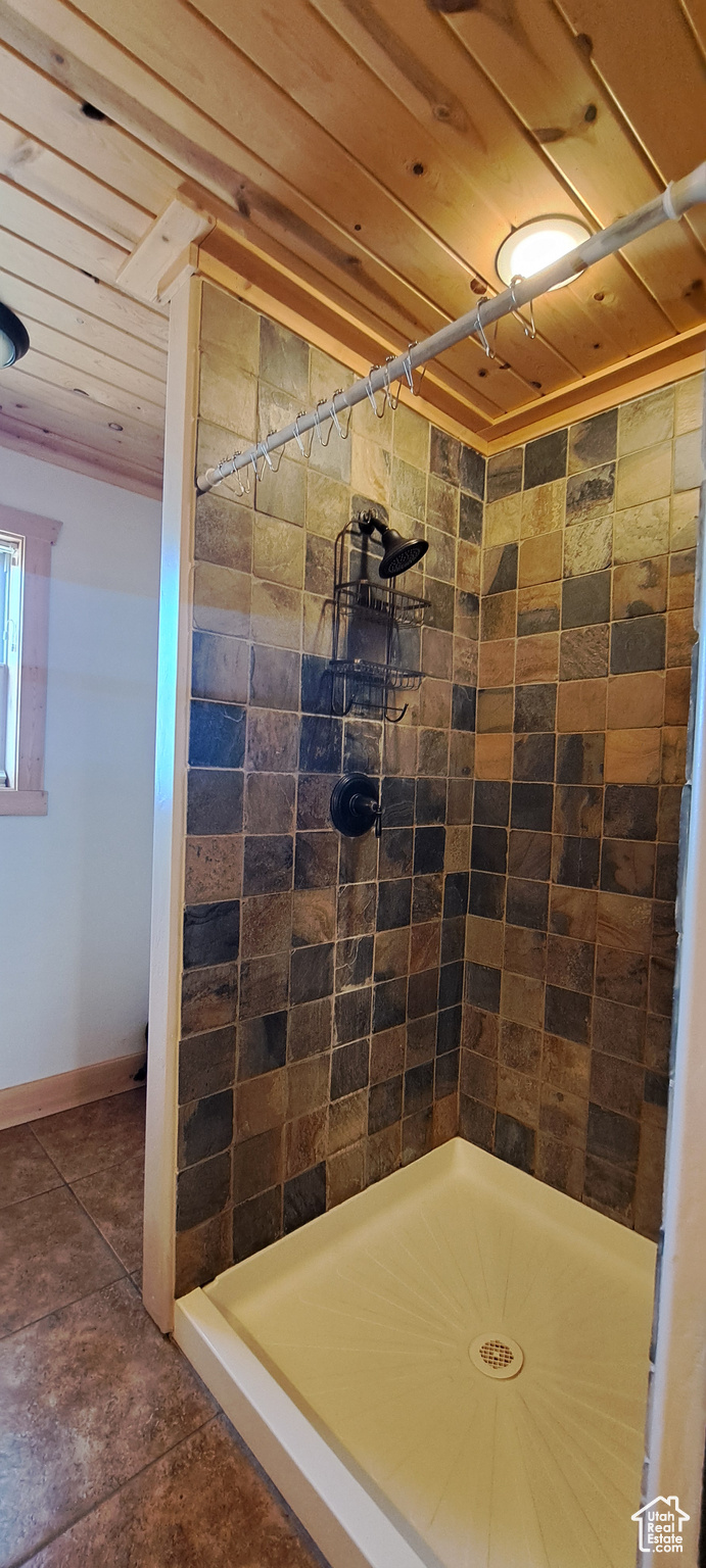 Bathroom with tile flooring, wooden ceiling, and a tile shower
