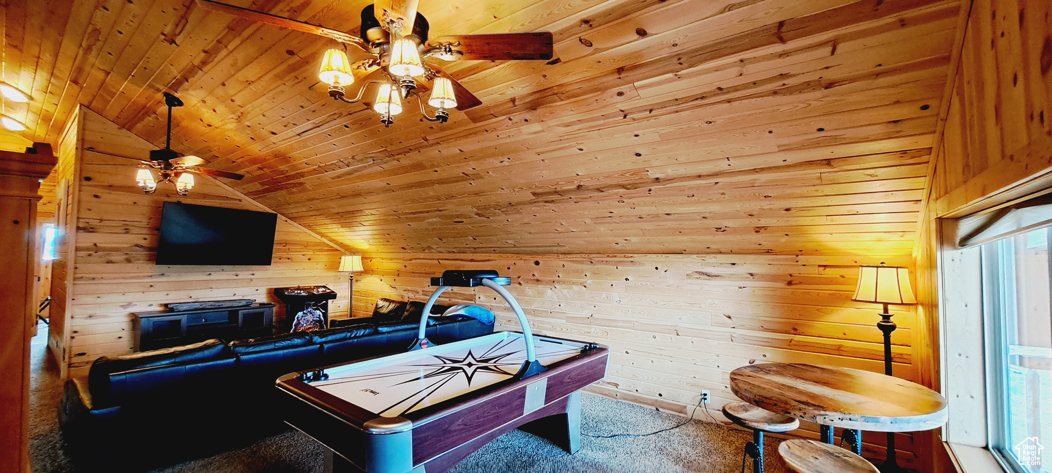 Rec room featuring ceiling fan, lofted ceiling, wooden walls, wood ceiling, and carpet