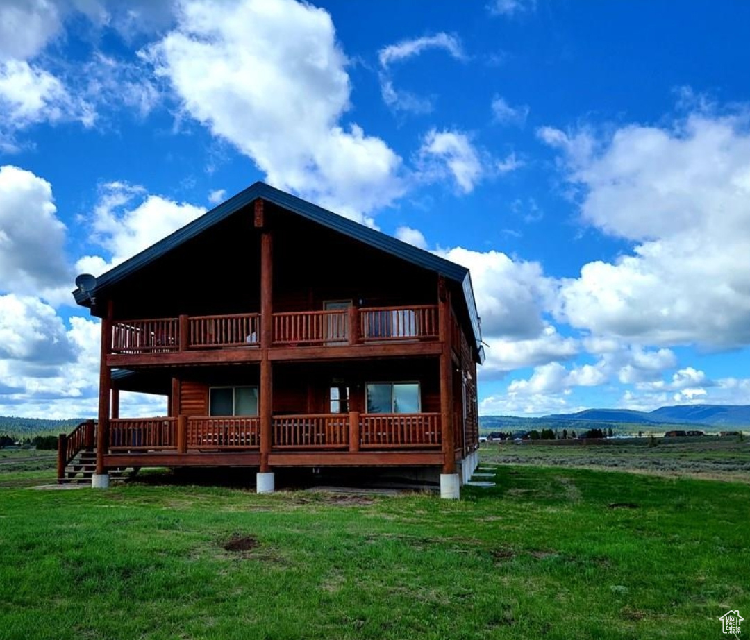 Rear view of house featuring a deck with mountain view and a lawn