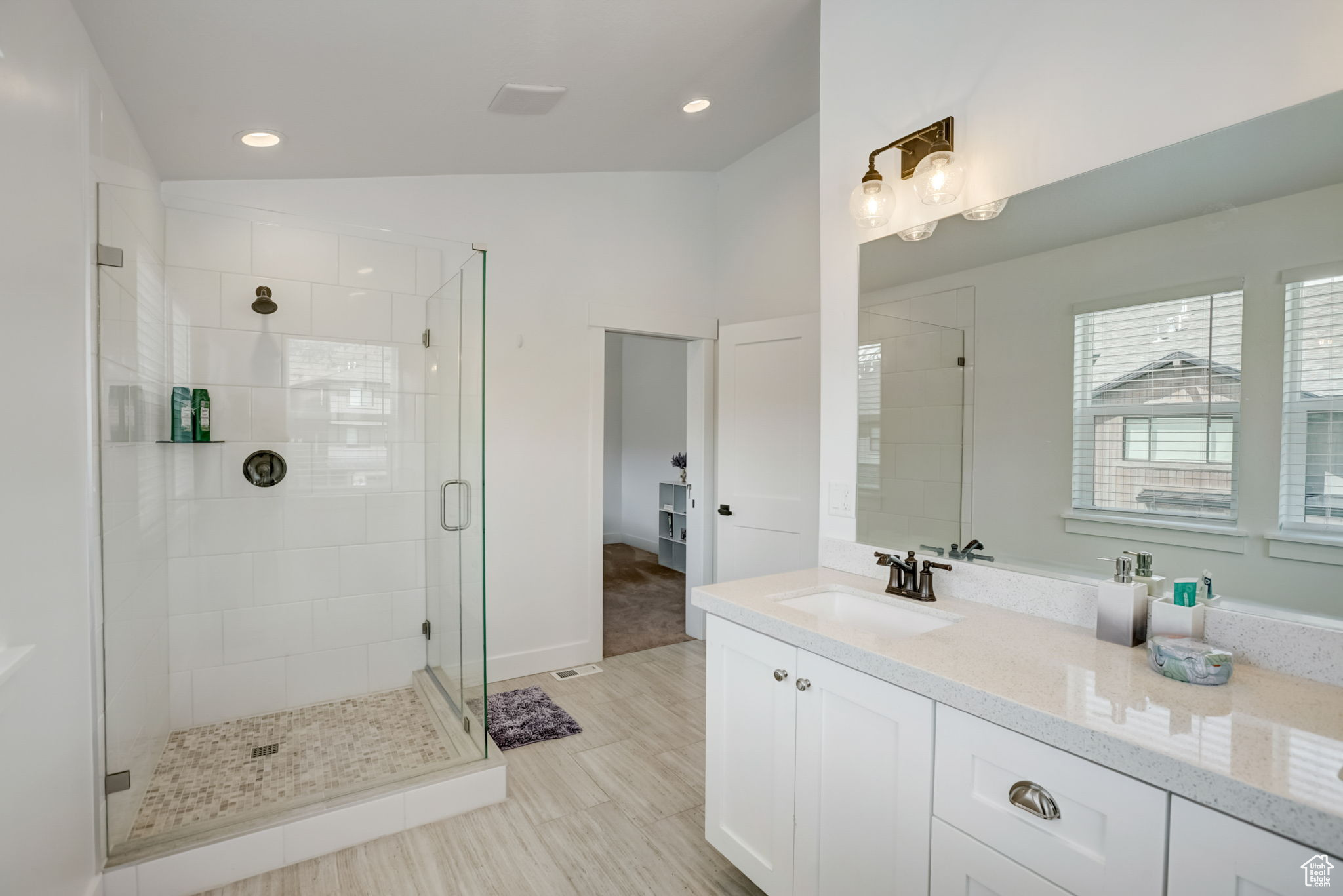 Bathroom featuring lofted ceiling, large vanity, an enclosed shower, and tile flooring