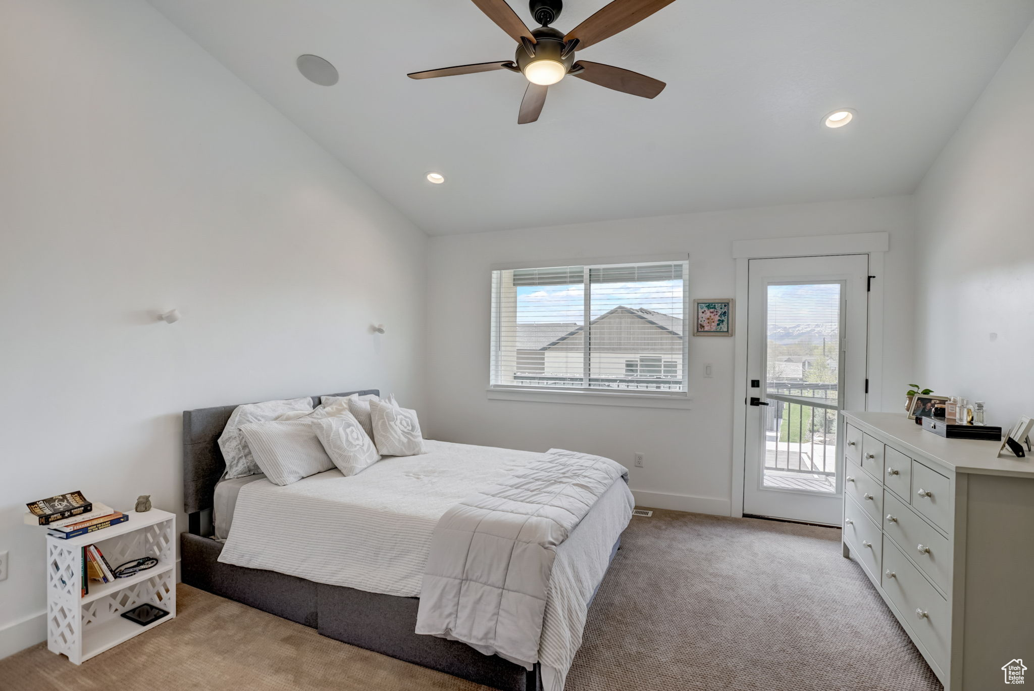 Carpeted bedroom featuring ceiling fan, vaulted ceiling, and access to exterior