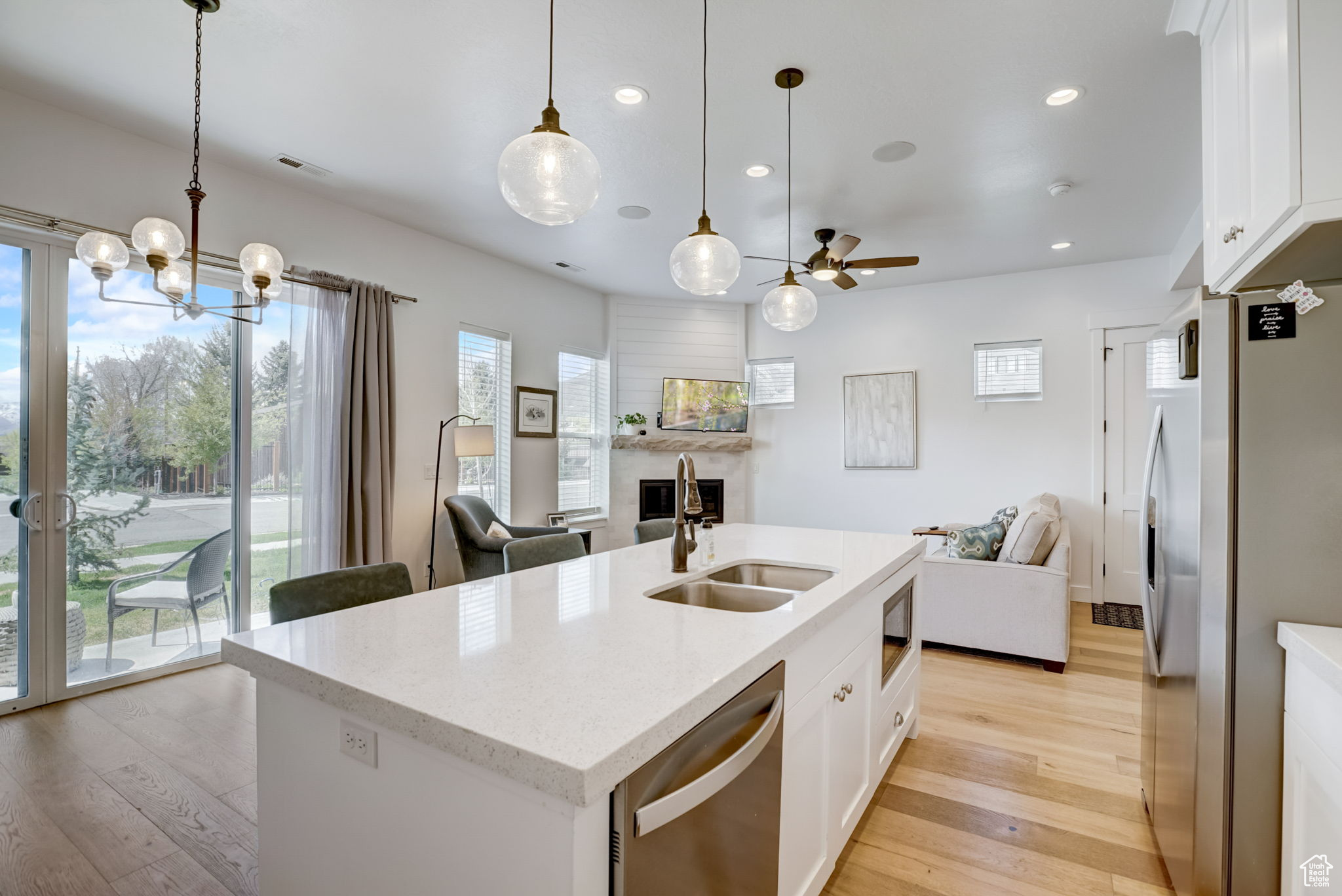 Kitchen featuring white cabinets, light hardwood, sink, and a center island with sink