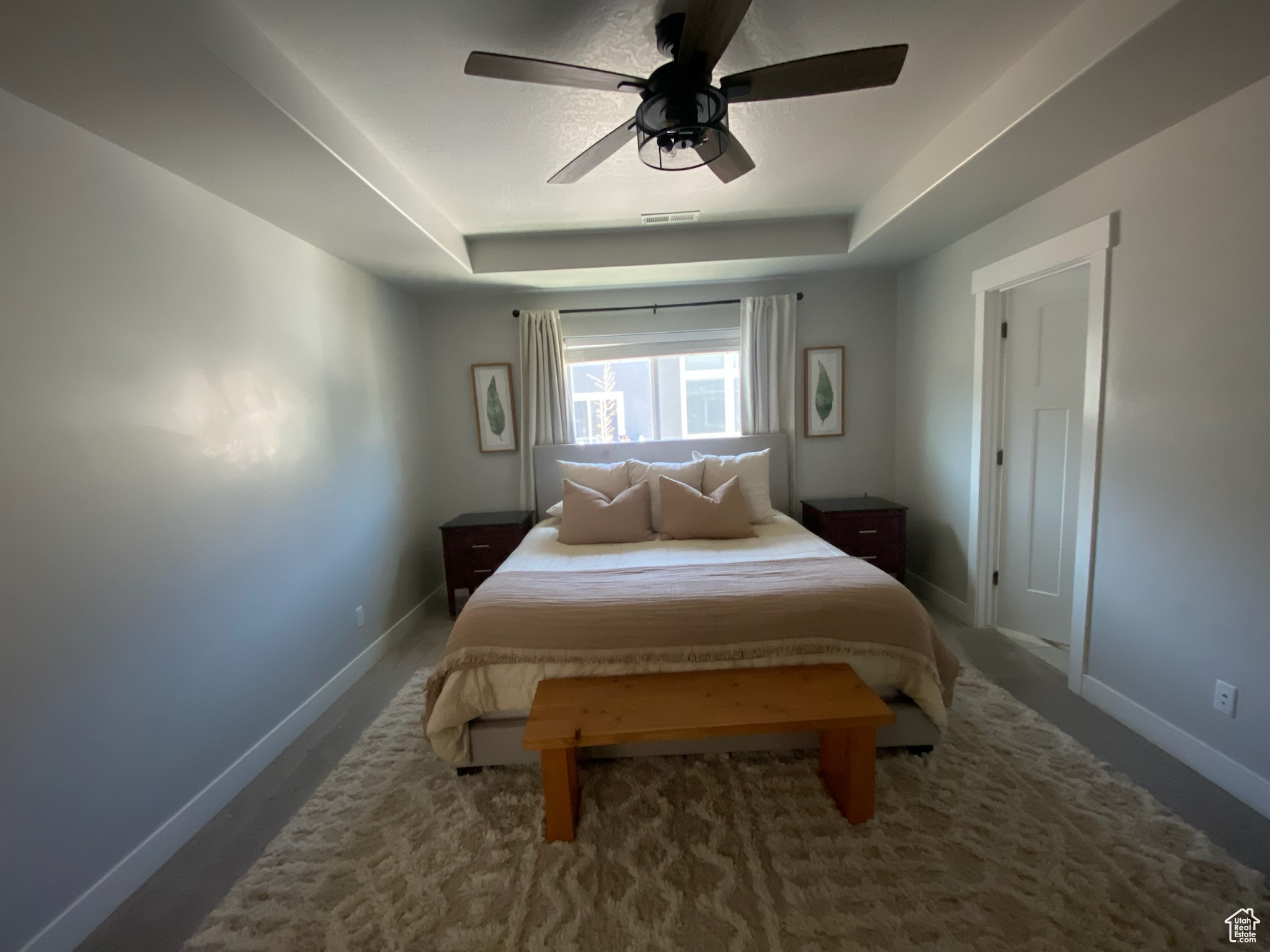 Bedroom with a raised ceiling and ceiling fan