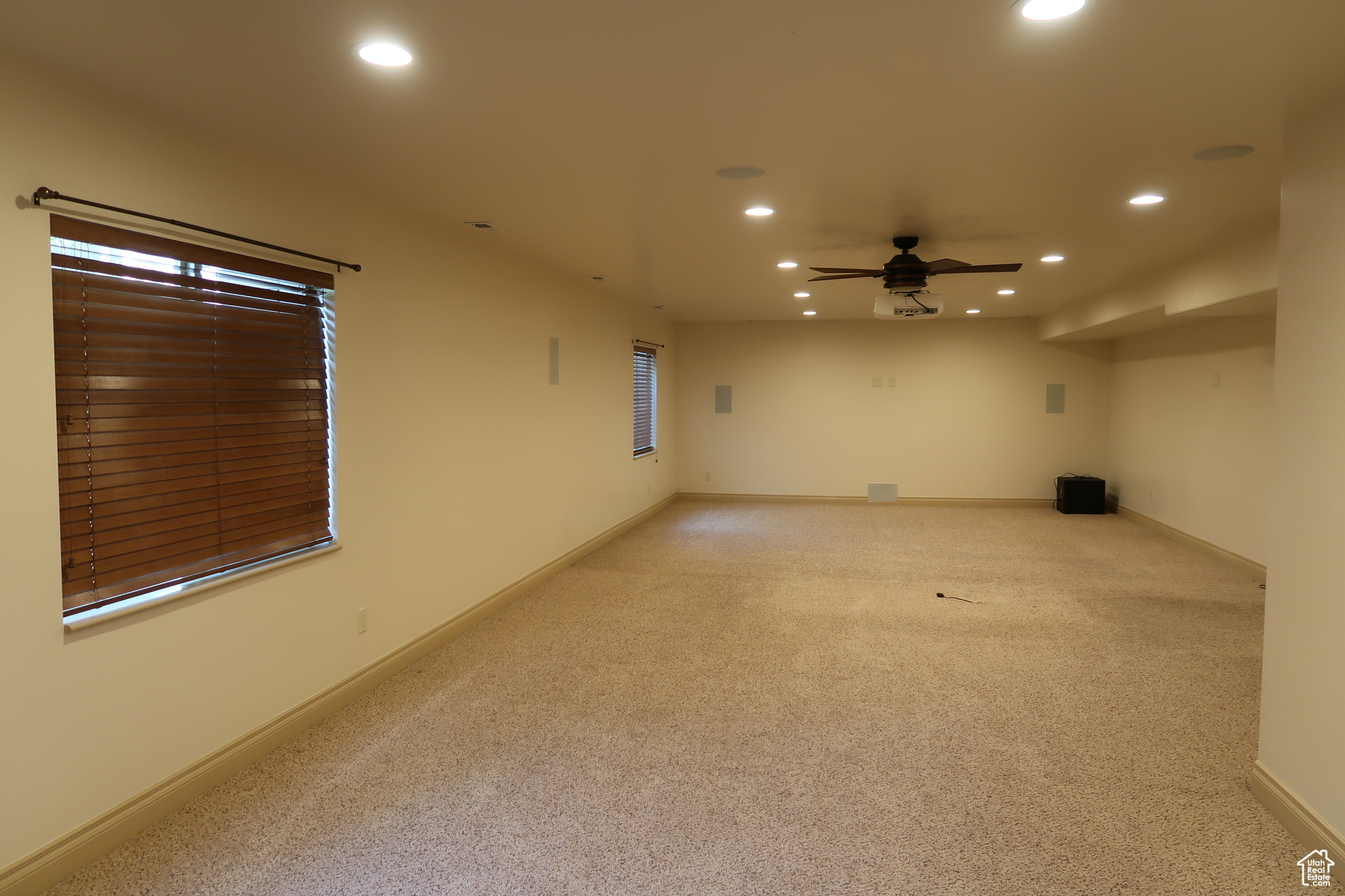 Carpeted spare room featuring ceiling fan and built-in theater projector