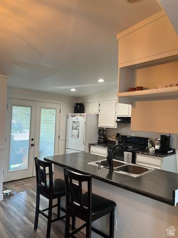 Kitchen featuring french doors, hardwood / wood-style flooring, white cabinets, a kitchen breakfast bar, and white refrigerator